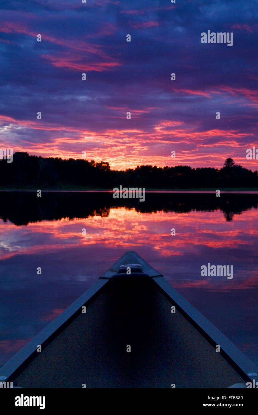 Una canoa indica il tramonto sbiadito su un tranquillo lago del Minnesota. Foto Stock