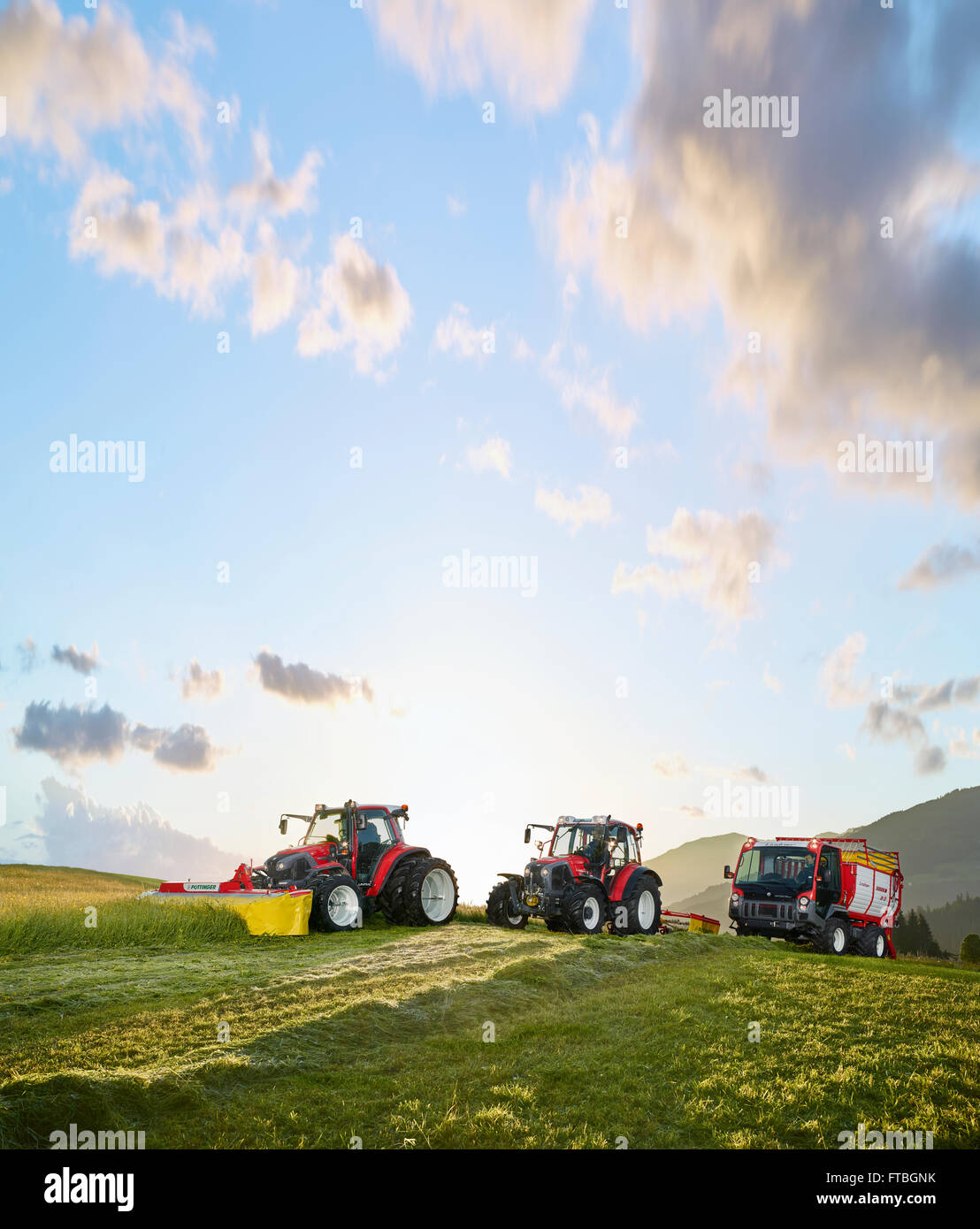 Tre veicoli, due trattori ed un trasportatore la falciatura di prati, Hopfgarten, Brixental Tirolo, Austria Foto Stock