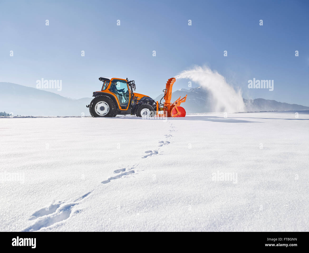 Trattore con un ventilatore di neve la rimozione di neve, servizi invernali, Kundl, Valle Inn, Distretto di Kufstein, Tirolo, Austria Foto Stock