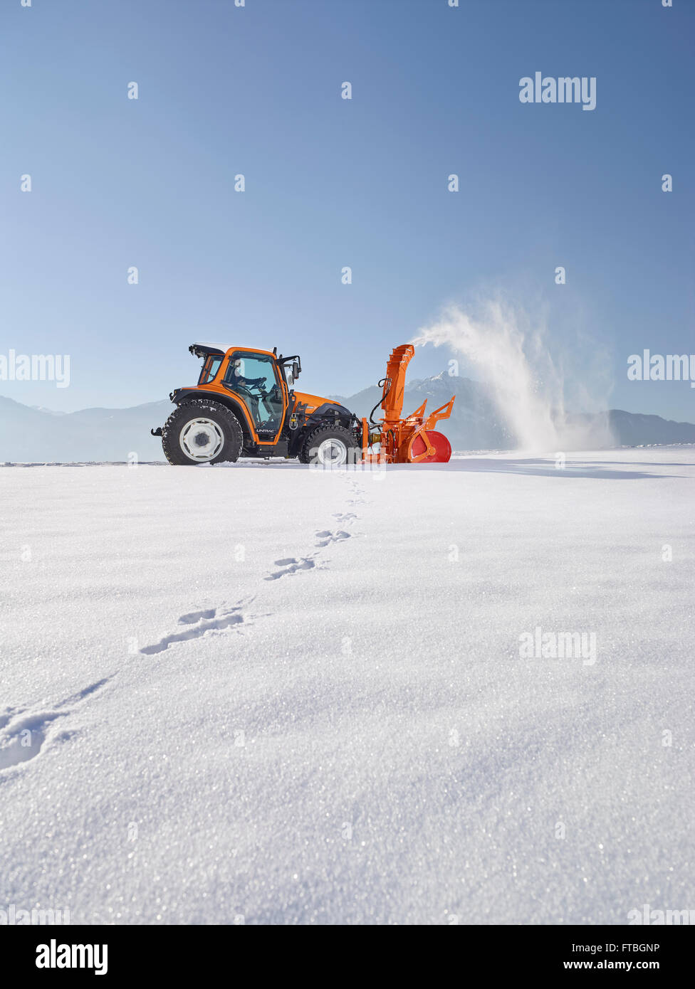 Trattore con un ventilatore di neve la rimozione di neve, servizi invernali, Kundl, Valle Inn, Distretto di Kufstein, Tirolo, Austria Foto Stock