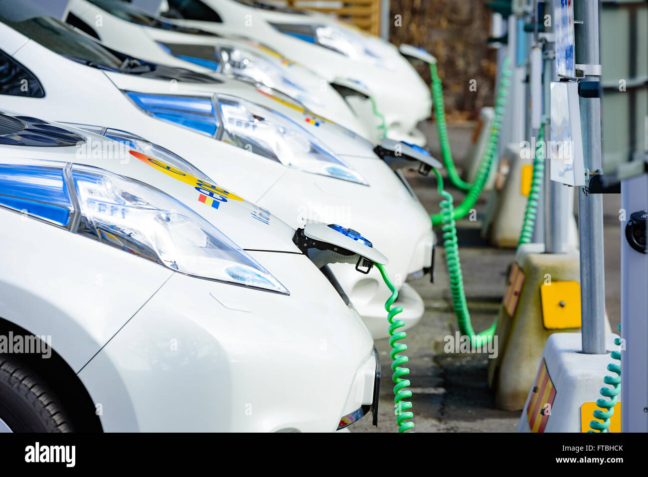 Kristianstad, Svezia - 20 Marzo 2016: la carica di qualche bianco Nissan auto elettriche. Verde cavi a spirale sono attaccati a th Foto Stock