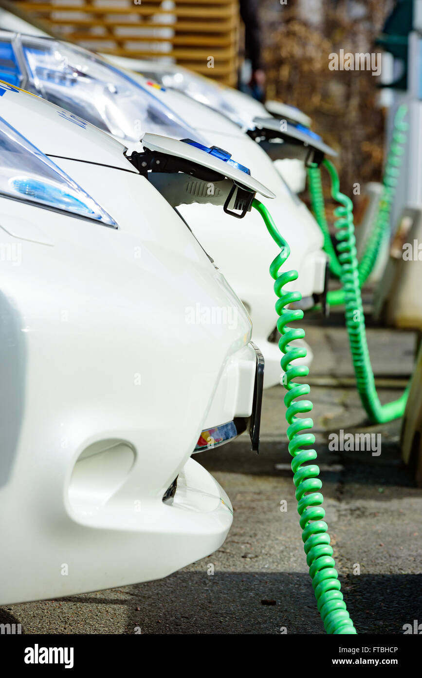 Kristianstad, Svezia - 20 Marzo 2016: la carica di qualche bianco Nissan auto elettriche. Verde cavi a spirale sono attaccati a th Foto Stock