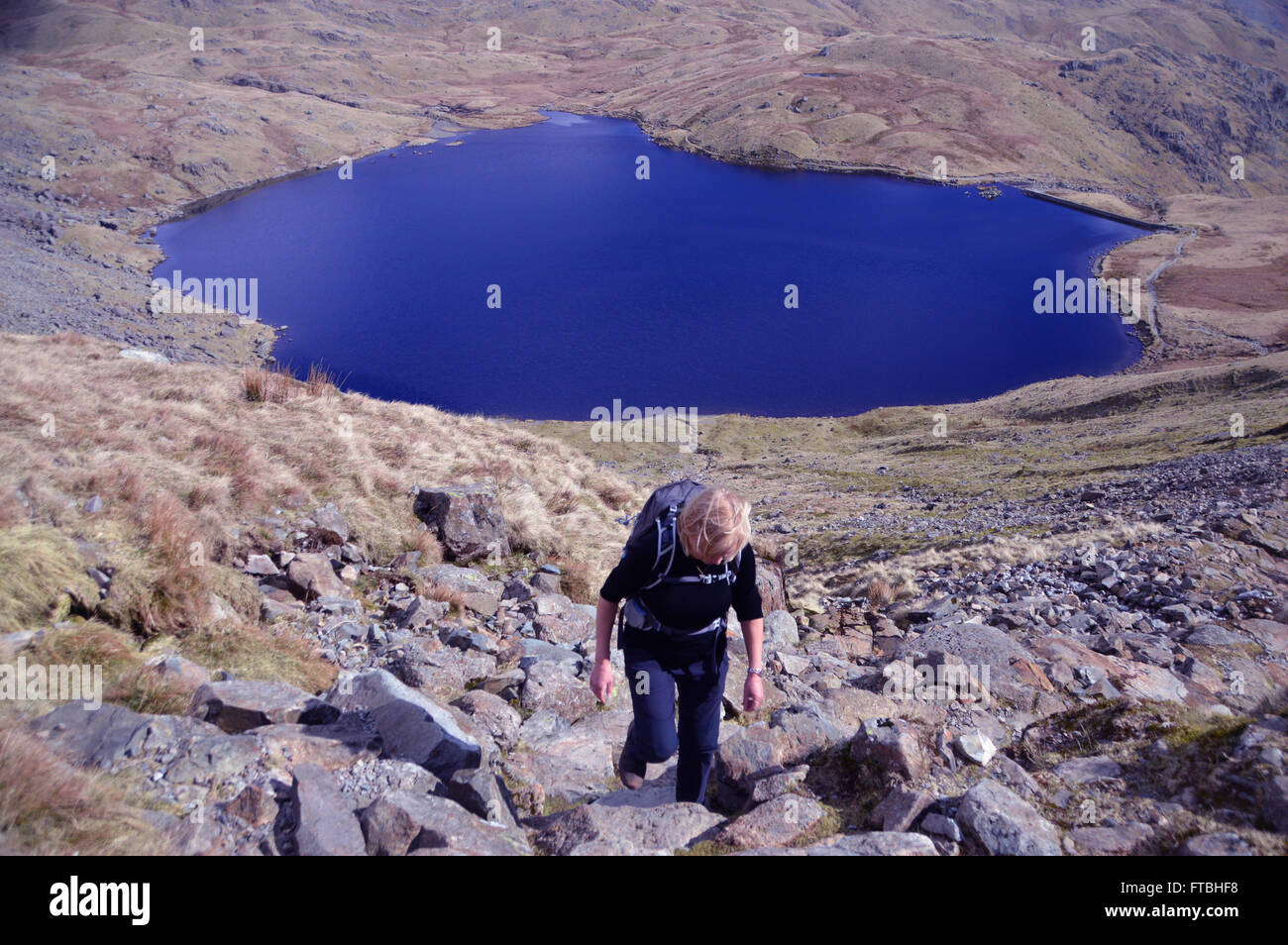 Lone dai capelli biondi Donna Sopra Arrampicata Stickle Tarn Langdale,Cumbria Regno Unito. Foto Stock