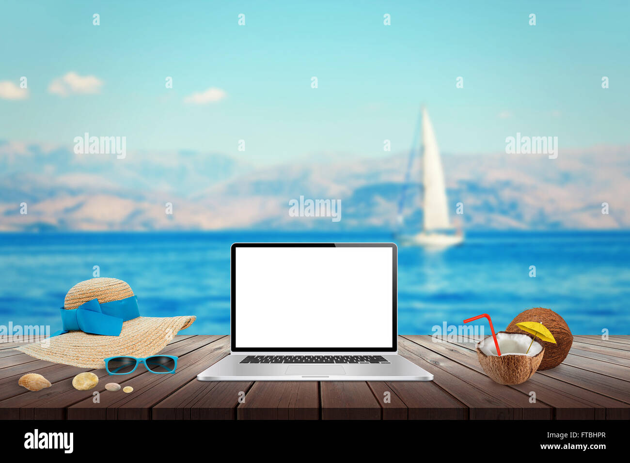Visualizzazione isolata del computer portatile sul tavolo di legno per mockup. Noce di cocco, hat, conchiglie, pietre, gli occhiali da sole sul tavolo. Mare, yacht Foto Stock