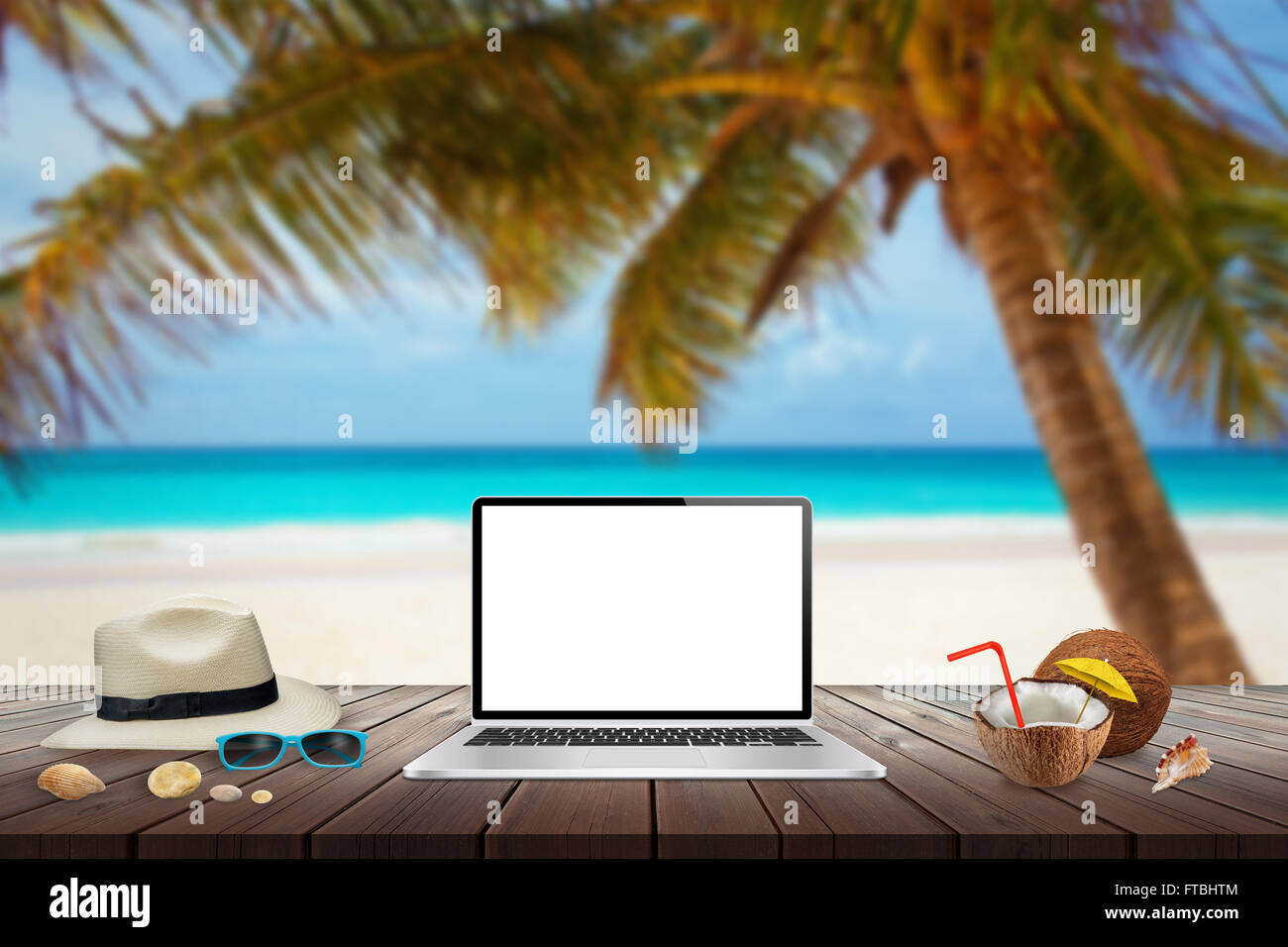Visualizzazione isolata del computer portatile sul tavolo di legno per mockup. Noce di cocco, hat, conchiglie, pietre, gli occhiali da sole sul tavolo. Spiaggia, mare, palm Foto Stock