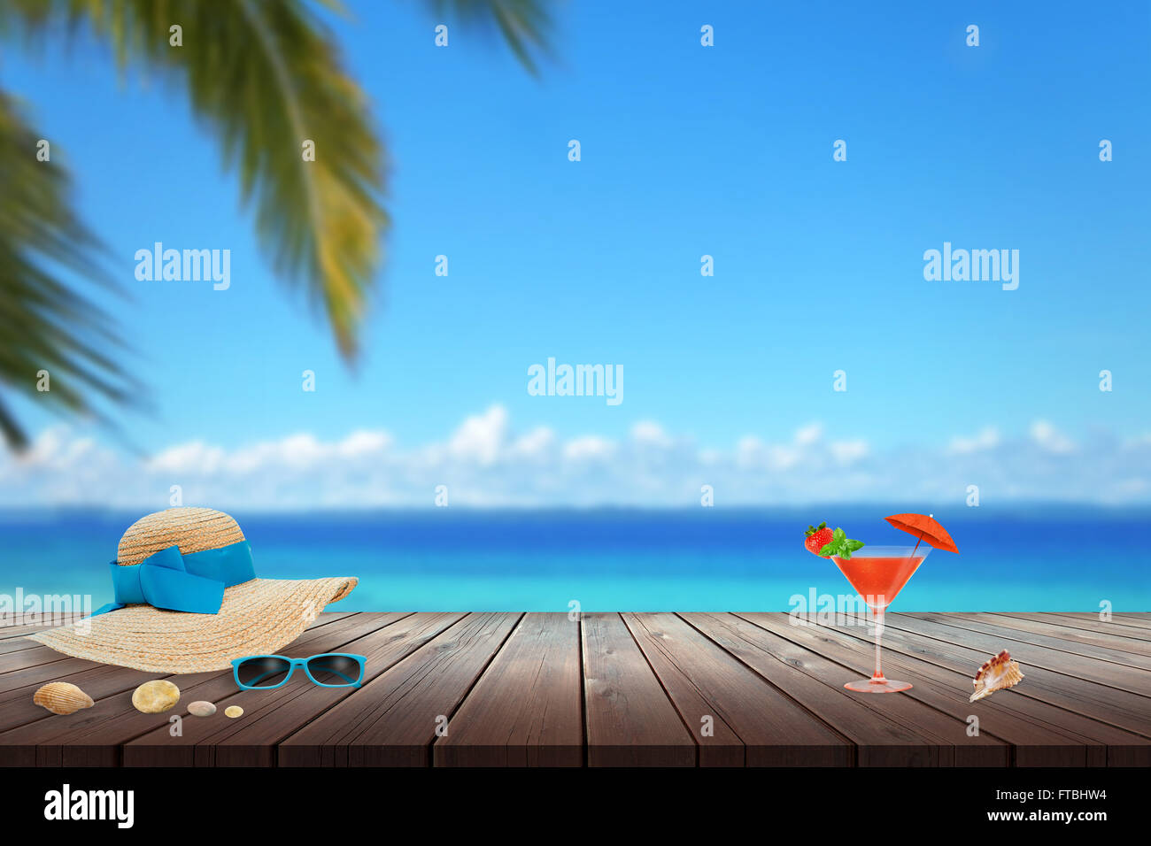Cappello, occhiali da sole, cocktail, shell sulla spiaggia tabella. Spazio libero per il testo. Spiaggia, mare, Palm e cielo blu in background. Foto Stock