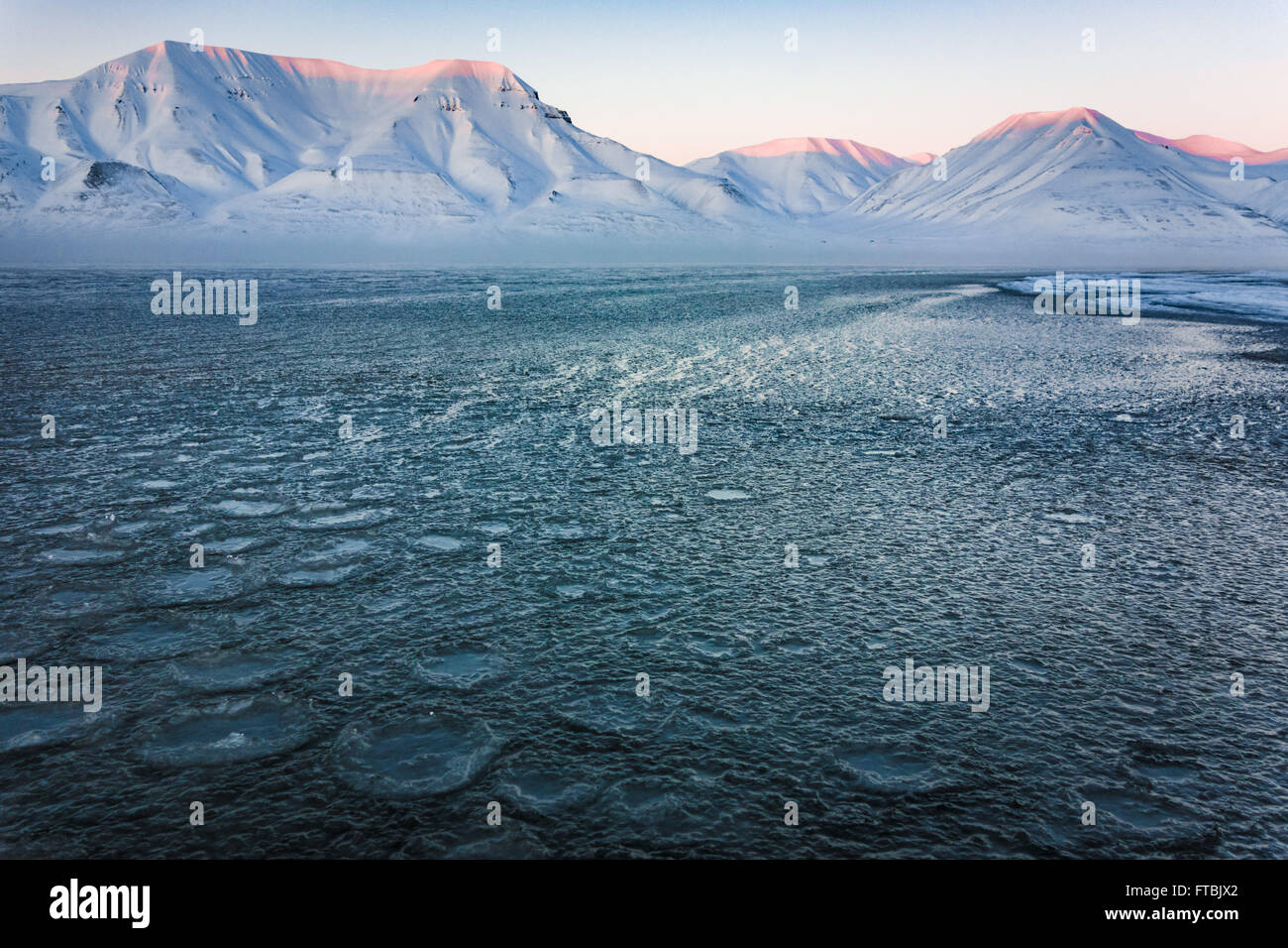 Tramonto litorale congelati a Sjøskrenten spiaggia con vedute Hiorthfjellet, Longyearbyen, Spitsbergen, Svalbard. Foto Stock