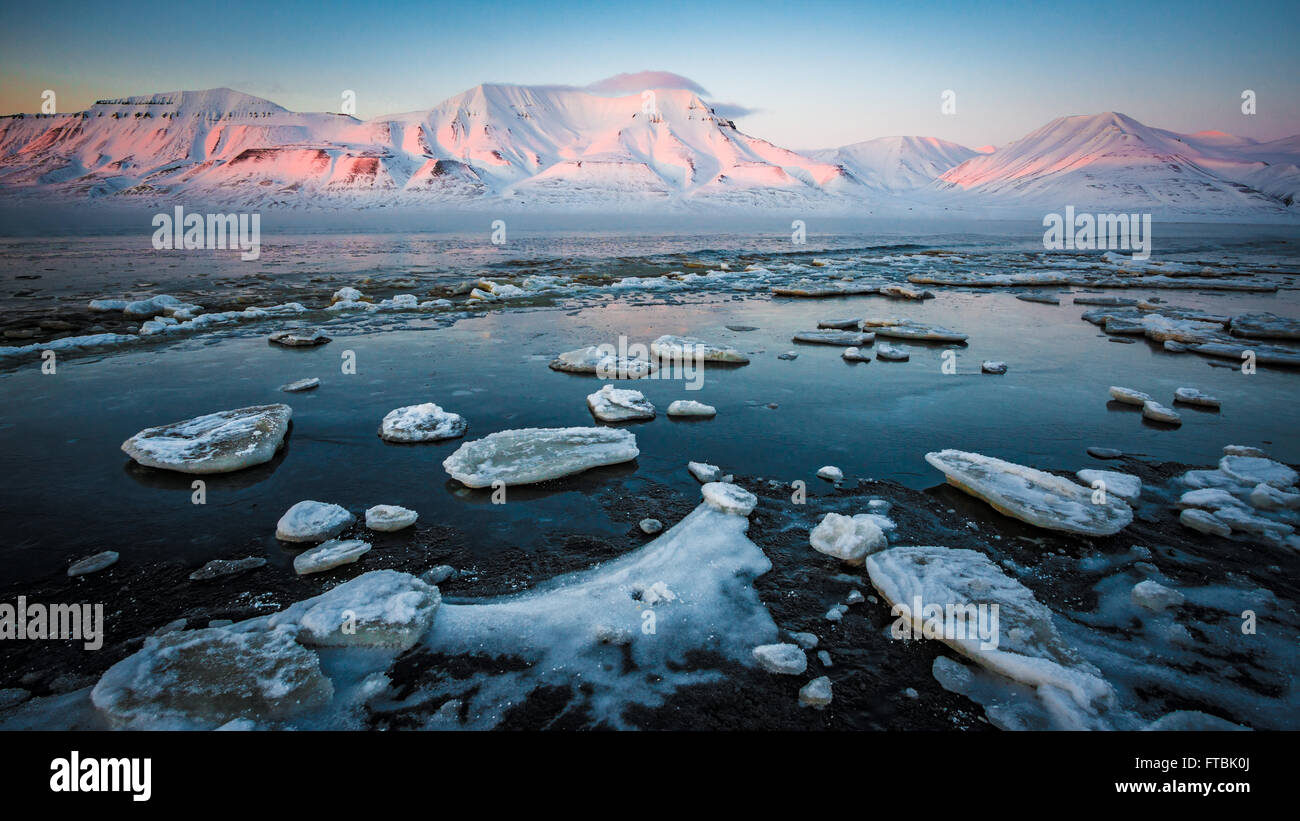 Tramonto litorale congelati a Sjøskrenten spiaggia con vedute Hiorthfjellet, Longyearbyen, Spitsbergen, Svalbard. Foto Stock