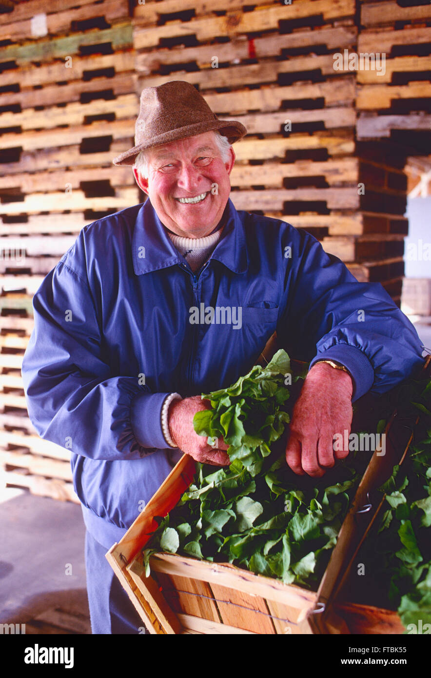 Ritratto del maschio sorridente contadino con prodotti freschi nel fienile Foto Stock