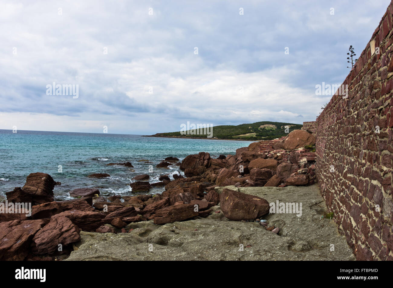 Muro fatto di rocce rosse alla spiaggia di Isola di San Pietro, Sardegna Foto Stock