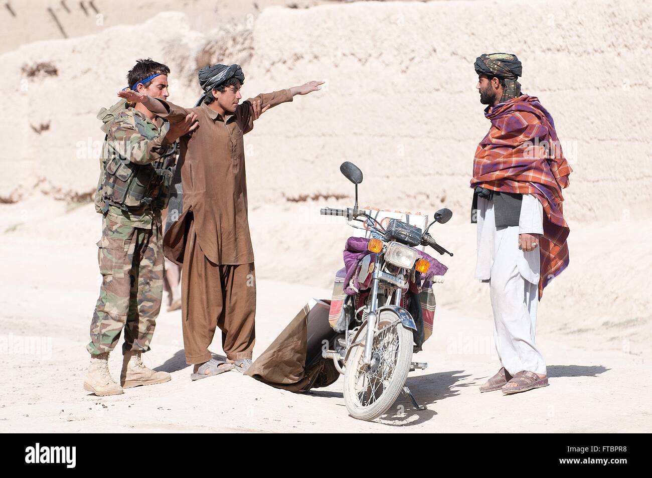 Un soldato con l esercito nazionale afgano 3° Brigata, frisks mentre gli abitanti del villaggio di pattuglia Giugno 14, 2012 in provincia di Ghazni, Afghanistan. Foto Stock