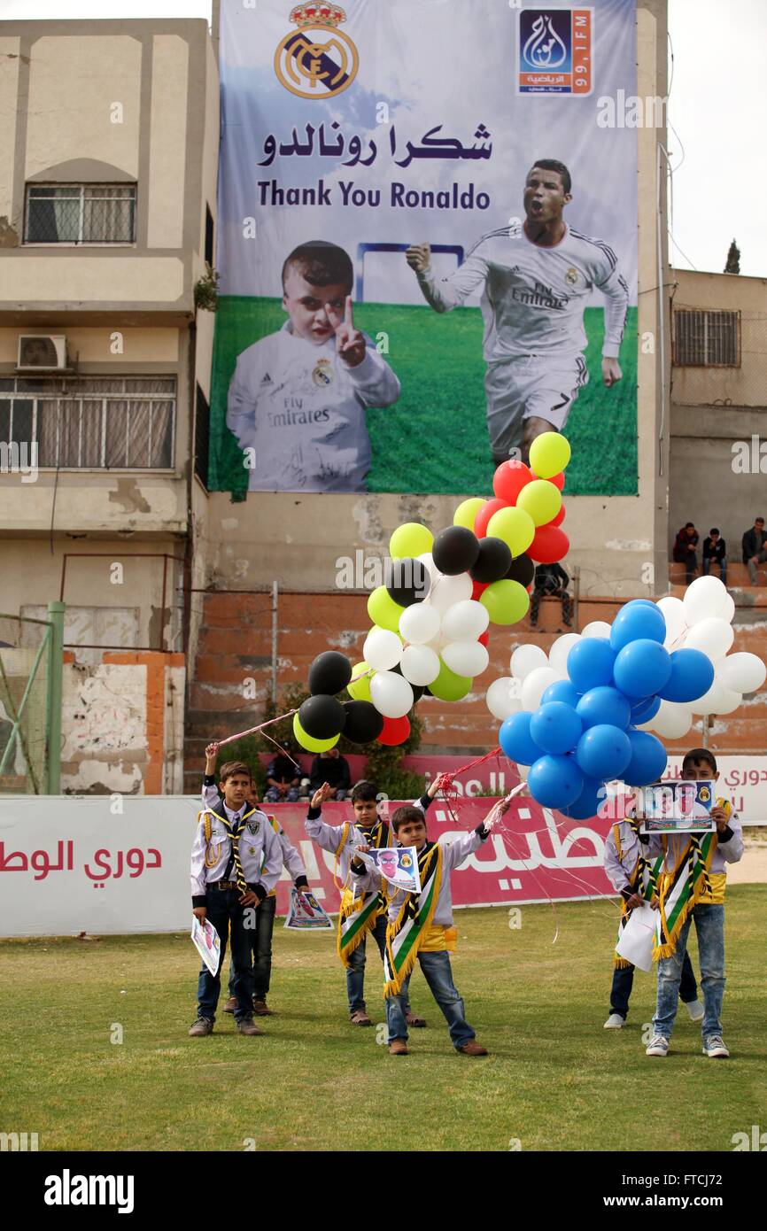 La città di Gaza, Striscia di Gaza, Territori palestinesi. 27 Mar, 2016. Chlidren palestinese tenere ballons e manifesti recanti un ritratto di ragazzo palestinese Ahmed Dawabsha, 5, che hanno subito gravi ustioni in un incendio doloso da sospetti Jewish gli utenti malintenzionati sulla sua casa di famiglia lo scorso luglio e in cui il suo fratello più giovane, Ali, e i suoi genitori morirono entrambi, e Cristiano Ronaldo la stella del Real Madrid e scrisse in arabo ''Grazie Madrid . Grazie Ronaldo'' a Yarmouk Stadium di Gaza City il 27 marzo 2016. Ahmed recentemente tornato dalla Spagna, dove ha visitato del Real Madrid in campo di addestramento e ha incontrato il calcio spagnolo Foto Stock