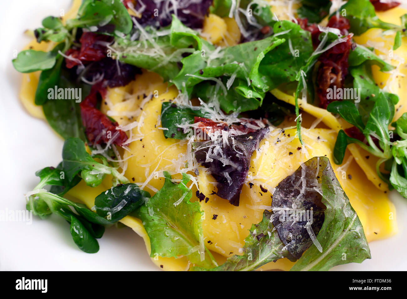 Cucina Italiana ravioli con insalata verde, formaggio parmigiano e patè di pomodoro. Foto Stock