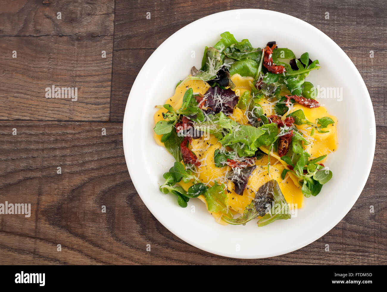 Cucina Italiana ravioli con insalata verde, formaggio parmigiano e patè di pomodoro. Foto Stock