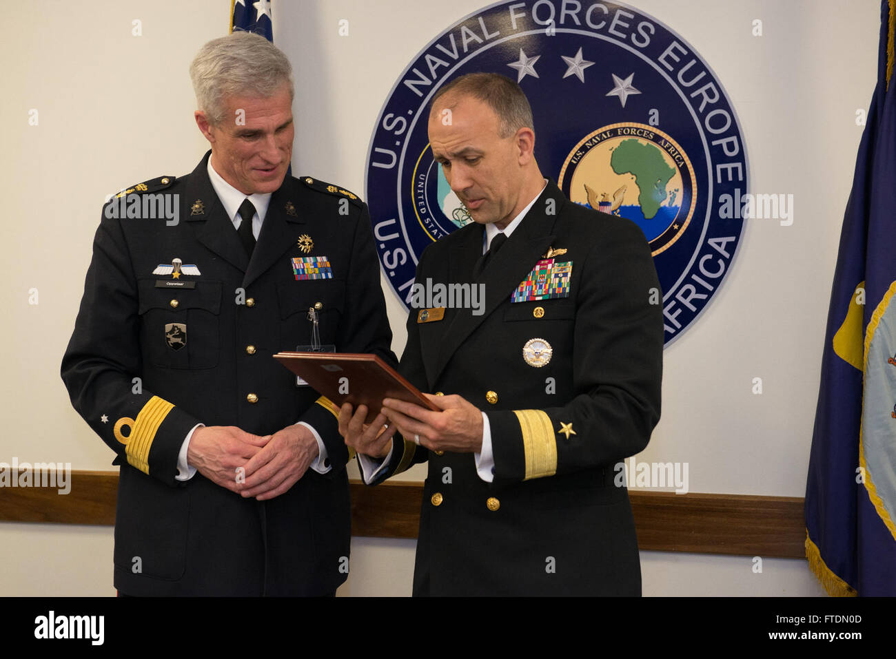 Questa immagine cattura Cathal o'Connor, capo di stato maggiore delle forze navali USA Europa-Africa, scambiando regali con il brigadiere Richard Oppelaar, comandante generale del corpo dei Marine dei Paesi Bassi reali. L'incontro, tenutosi presso il quartier generale della 6th Fleet a Napoli, riflette la cooperazione in corso tra gli alleati della NATO nelle operazioni di difesa. Foto Stock
