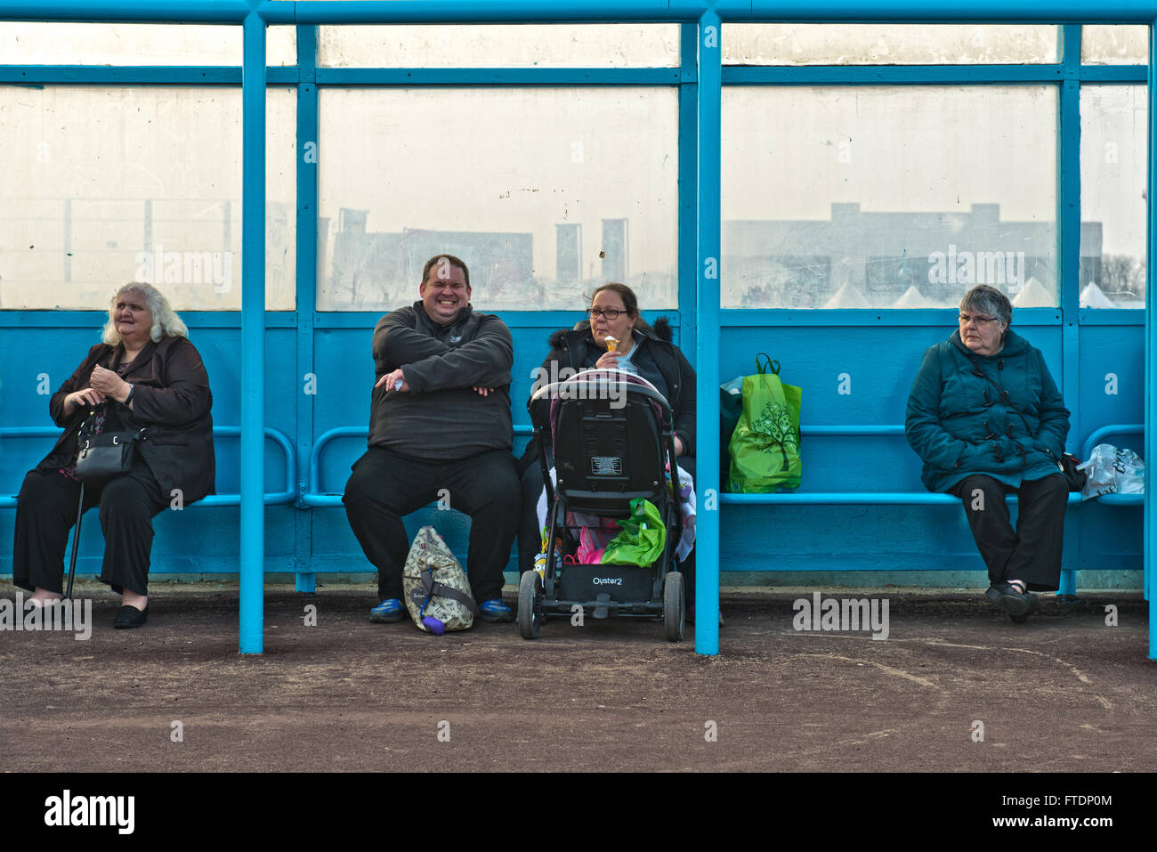 Una candida immagine di quattro persone sovrappeso seduti in una spiaggia rifugio a Skegness, Lincolnshire, Regno Unito Foto Stock