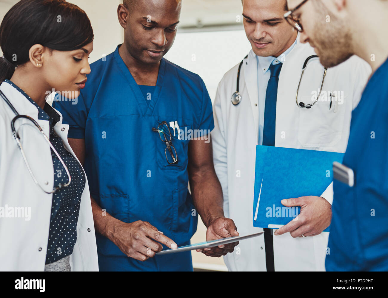 Il gruppo di medici e multirazziale consulenza permanente i record paziente su un computer tablet, vista ravvicinata Foto Stock