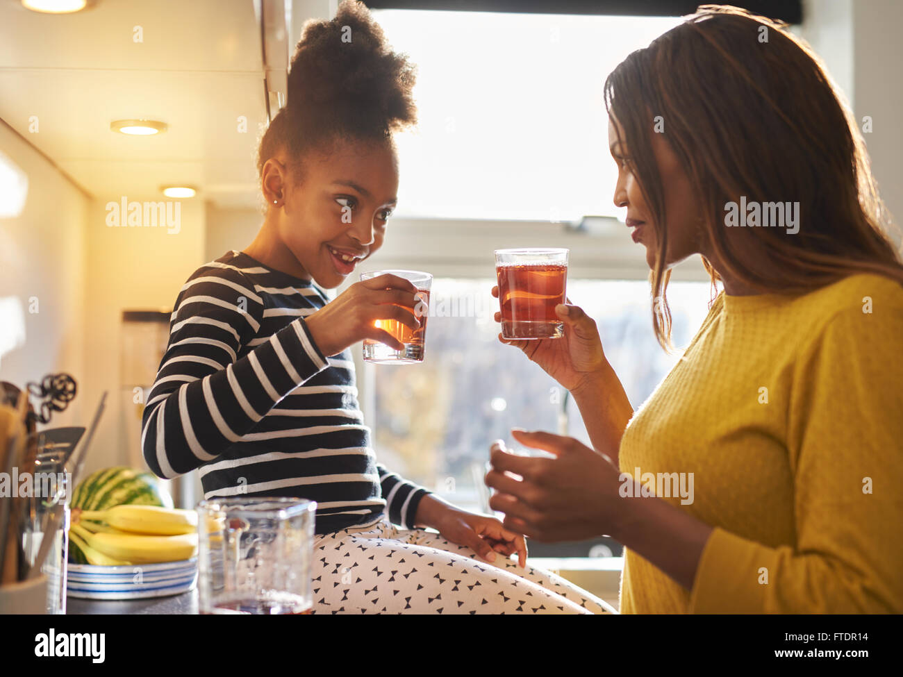 Mamma e Bambino in cucina a bere la limonata, sorridenti famiglia Foto Stock