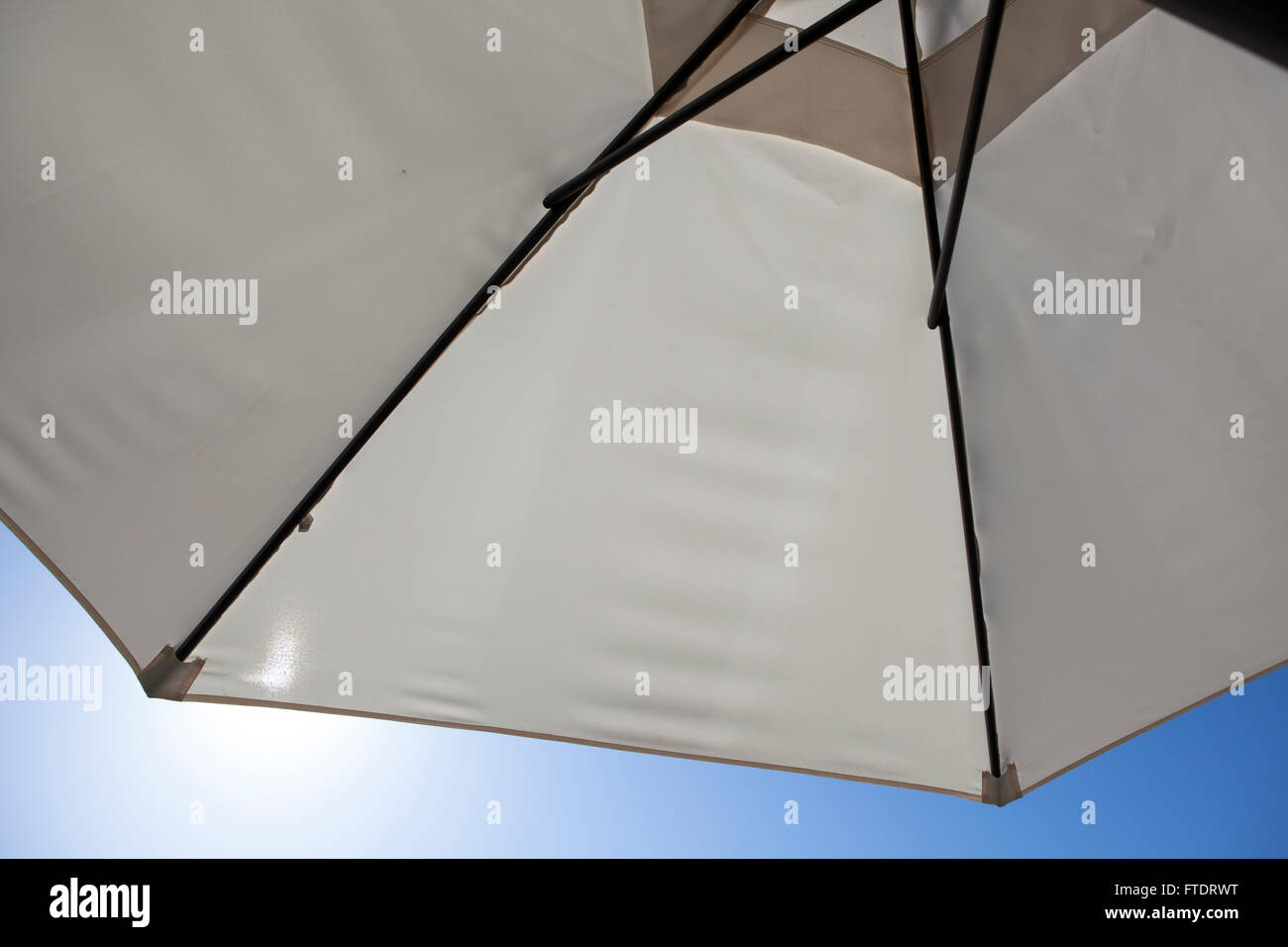 Una grande tela ombrello proteggendo il sitter seguito dalle dure sunshine impostato in un profondo cielo blu ed implicando il calore, estate, vacanze e relax. Foto Stock