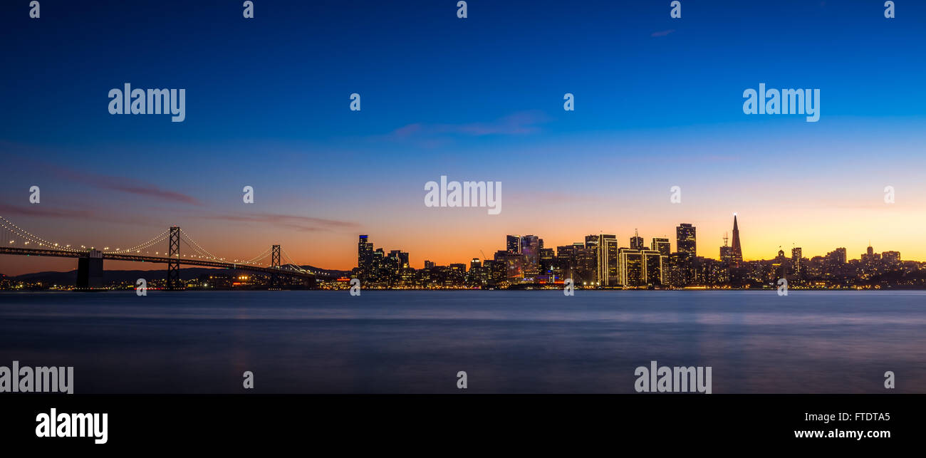 Skyline di San Francisco al tramonto con le luci della città e il Ponte della Baia Foto Stock