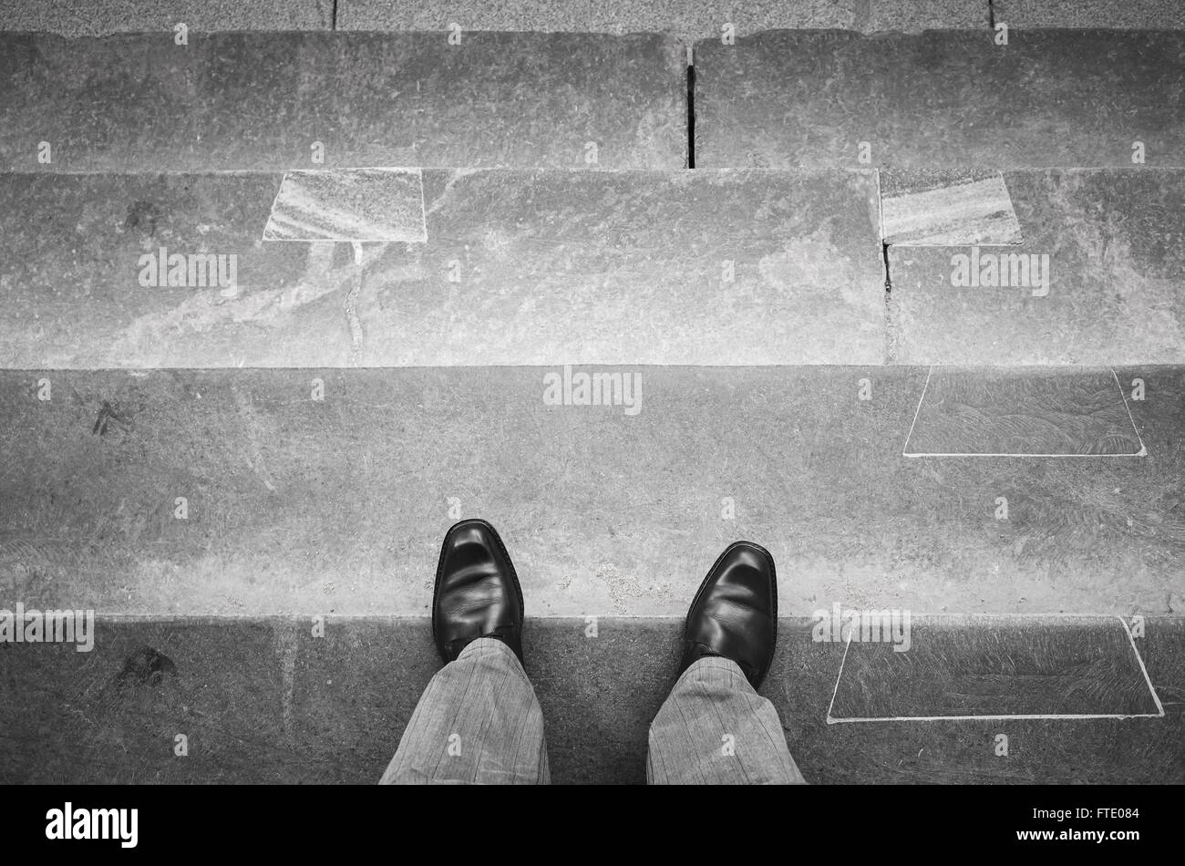 Urbanite man in black nuovi fulgidi scarpe di cuoio permanente sulla outdoor scale in pietra Foto Stock