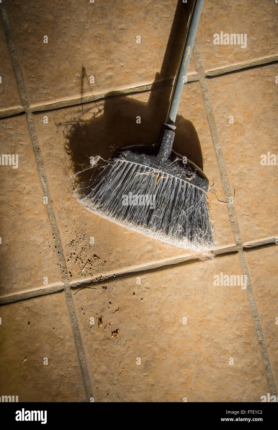 Scopa vecchia sul pavimento di piastrelle con il mucchio di sporcizia Foto Stock