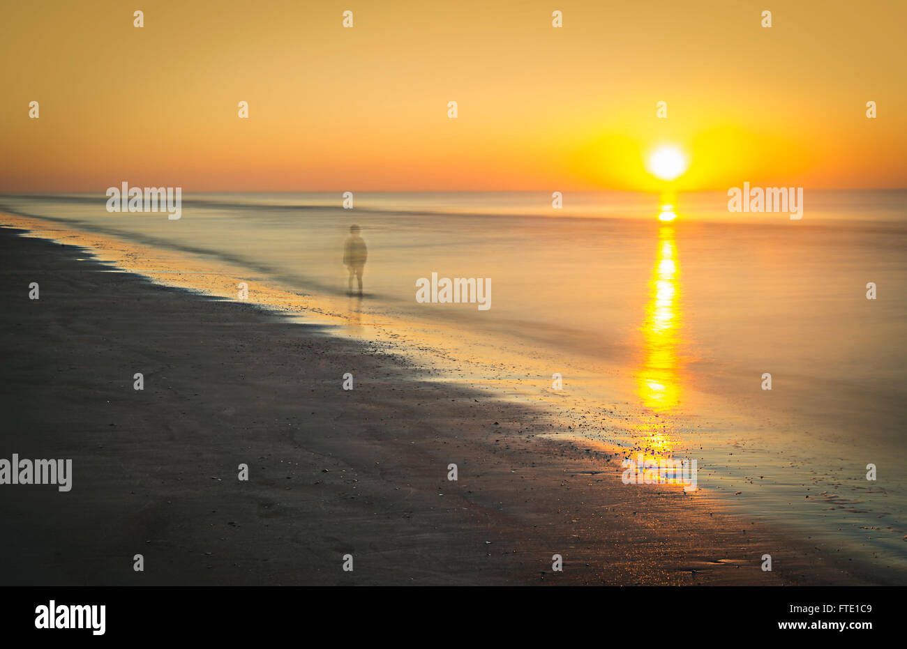 Triste fantasma della persona che cammina sulla spiaggia al tramonto Foto Stock