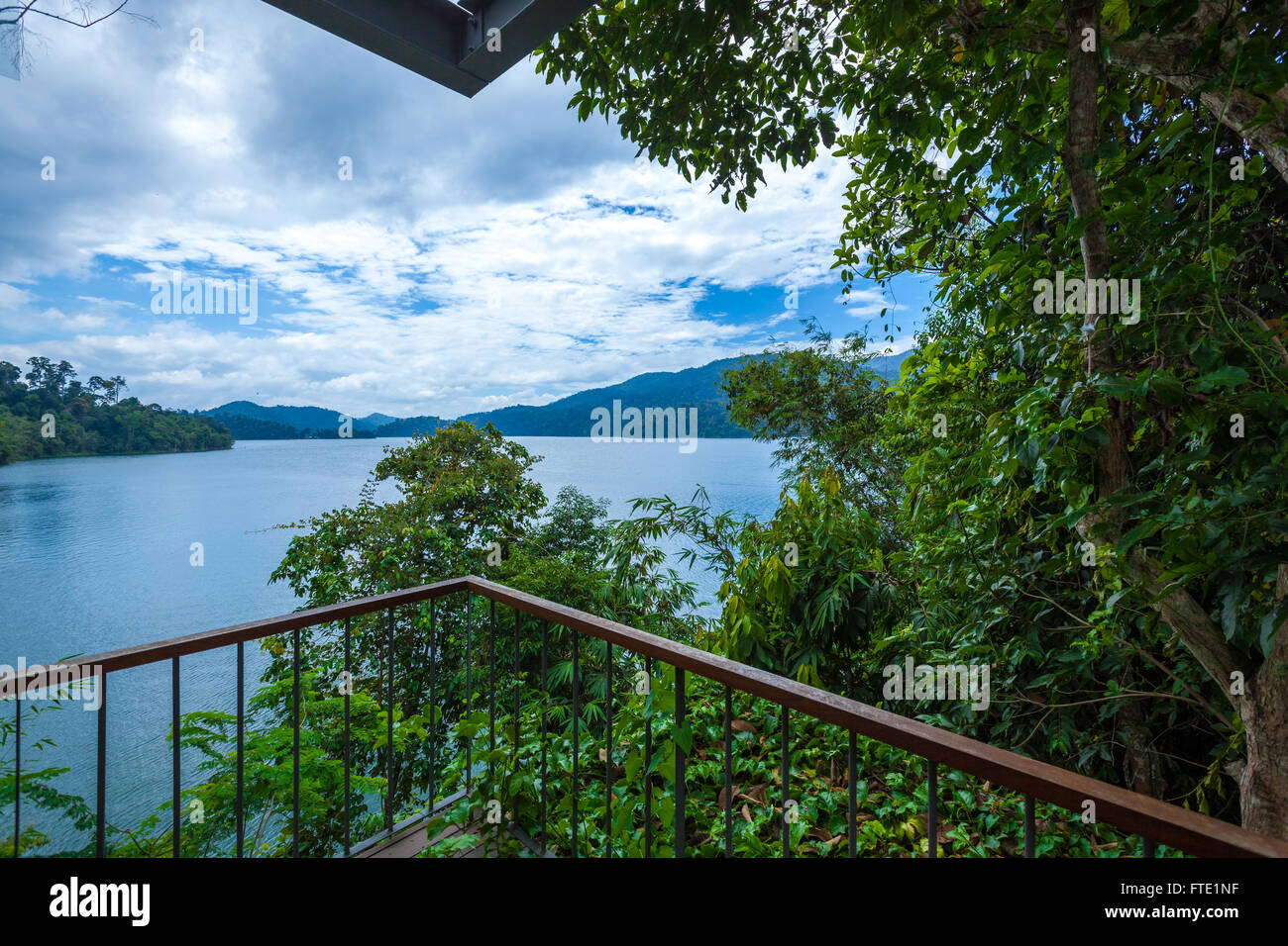 Un balcone panoramico che si affaccia su di una foresta pluviale tropicale, il lago e le isole di nuvoloso cielo blu. Belumè resort, striature Temenggor Lago. Foto Stock