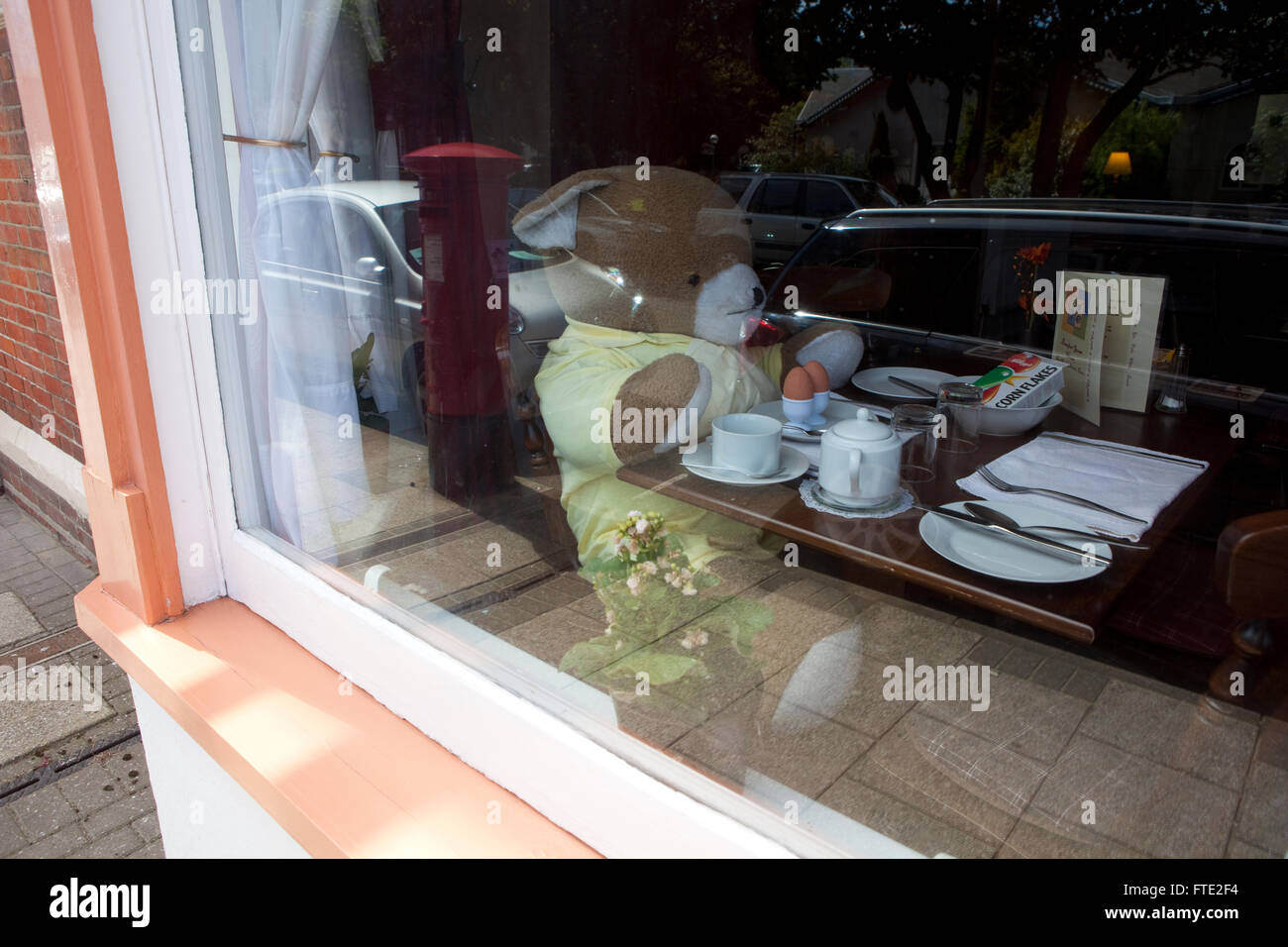 Un giocattolo childs bear siede in teh finestra di una guest house / hotel / B&B in un british holiday resort sul mare nel Regno Unito. Foto Stock