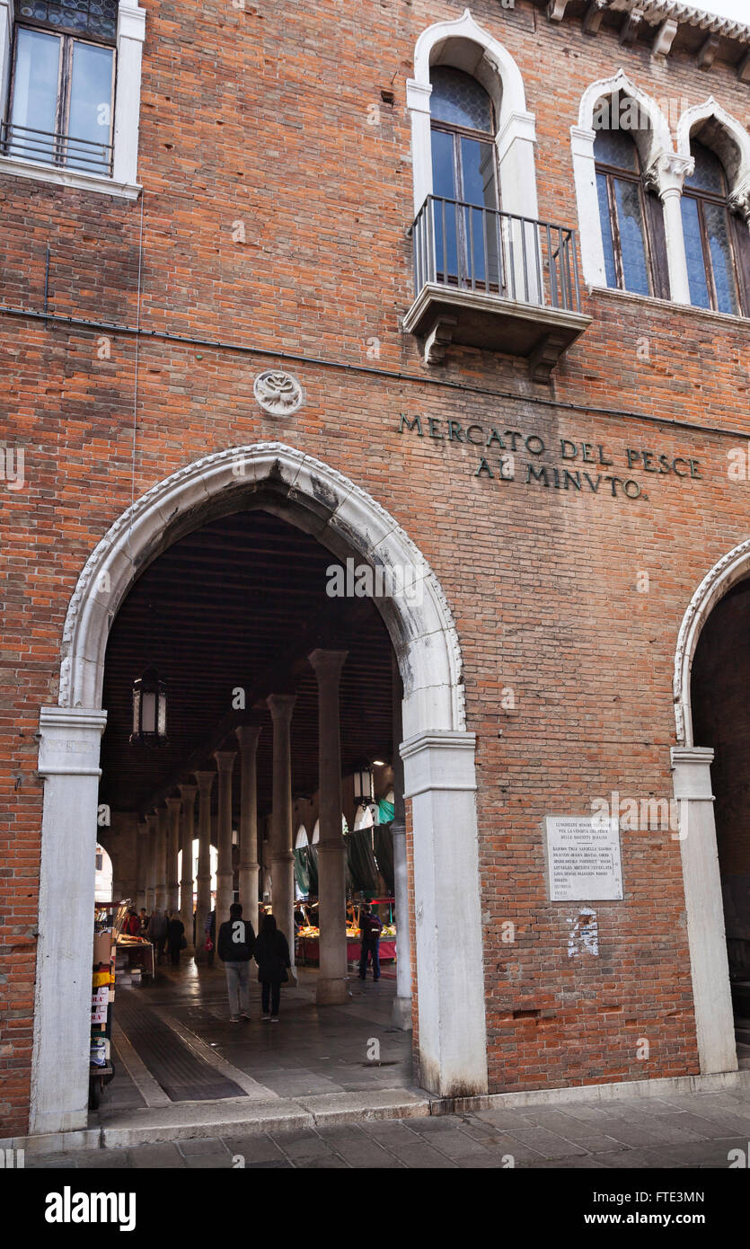 Ornato ingresso ad arco neo-gotico al mercato del pesce in mattoni che mostra gli interni e le persone saccheggiate al mercato Rialto di Venezia Foto Stock