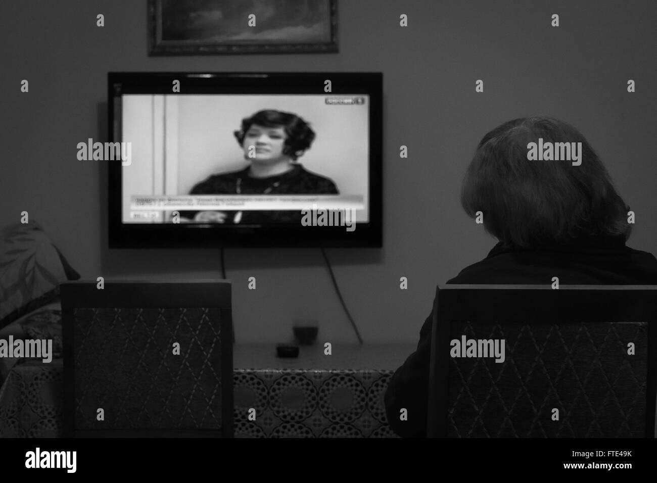 UFA - RUSSIA 3RD MARZO 2016 - Una donna anziana si siede e guarda un canale di notizie sulla televisione in un ambiente domestico durante il mese di marzo in U Foto Stock