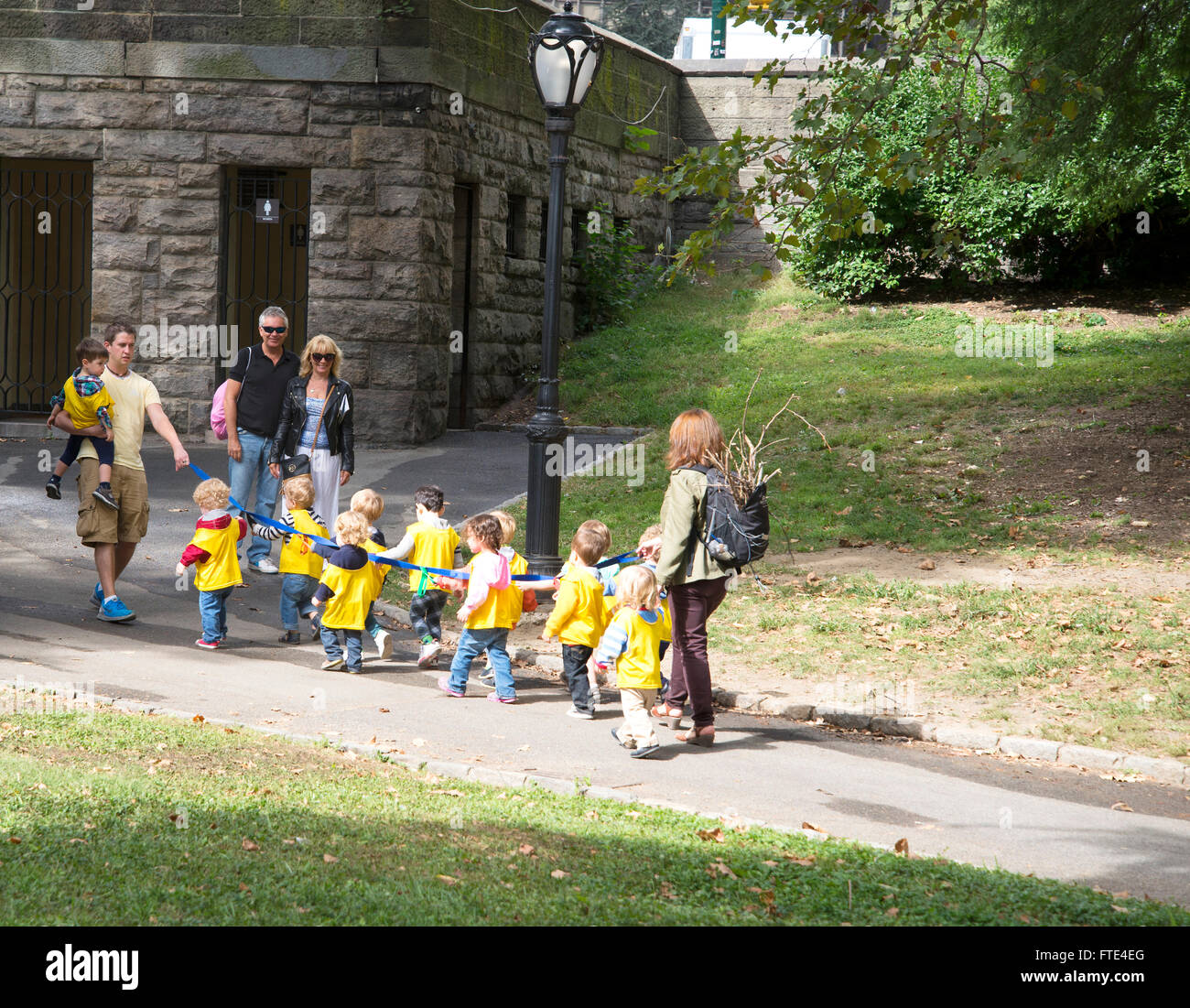 Un gruppo di bambini della scuola materna attesa e condividere lungo il nastro blu mentre si cammina nel Central Park di New York. Foto Stock