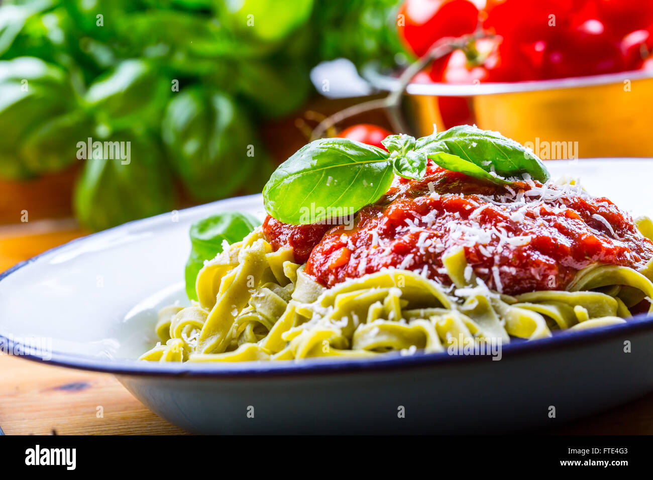 La pasta. Cucina italiana e mediterranea. Pasta Fettuccine con salsa di pomodoro foglie di basilico e aglio formaggio parmigiano. Foto Stock