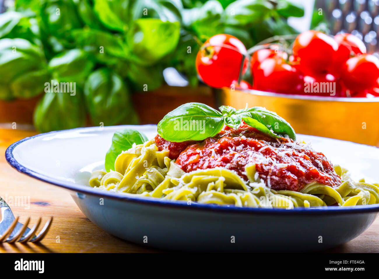 La pasta. Cucina italiana e mediterranea. Pasta Fettuccine con salsa di pomodoro foglie di basilico e aglio formaggio parmigiano. Foto Stock