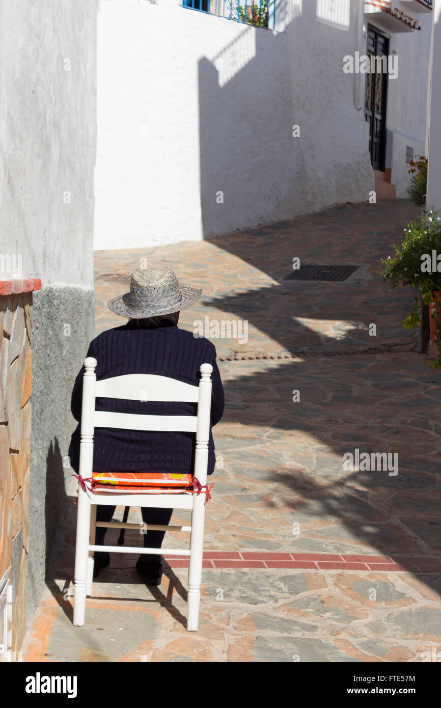 Vista posteriore dello spagnolo lady seduto in una sedia al di fuori della sua casa nel villaggio di Totalan, Malaga, Spagna meridionale. Foto Stock