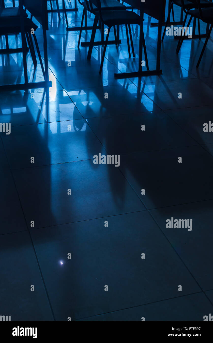 Righe e righe di conferenza vuota sedie catturati nella luce naturale del sole in una classe in ambiente scolastico. Nei toni del blu immagine con co Foto Stock