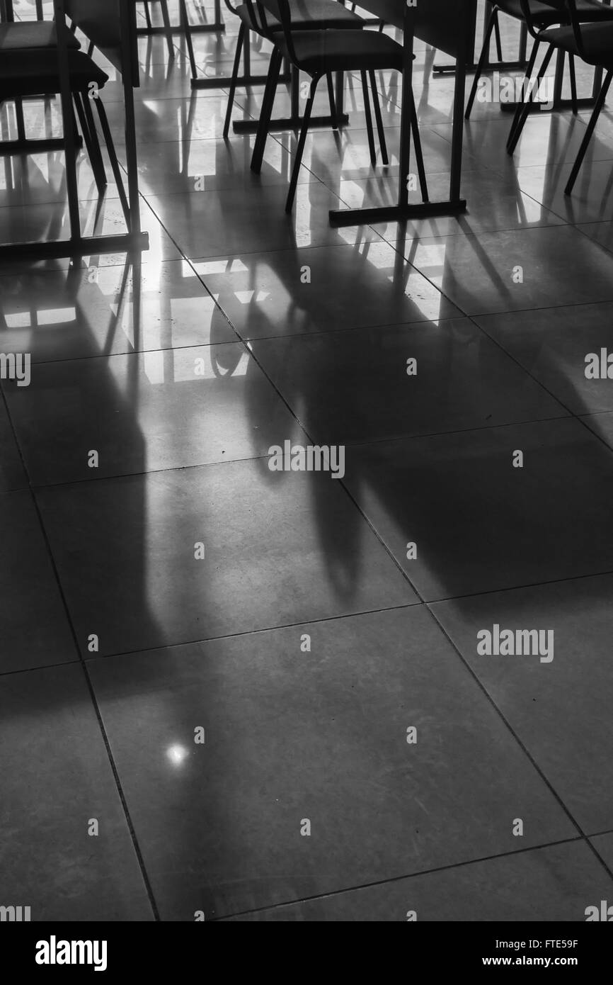Righe e righe di conferenza vuota sedie catturati nella luce naturale del sole in una classe in ambiente scolastico. Immagine in bianco e nero wi Foto Stock