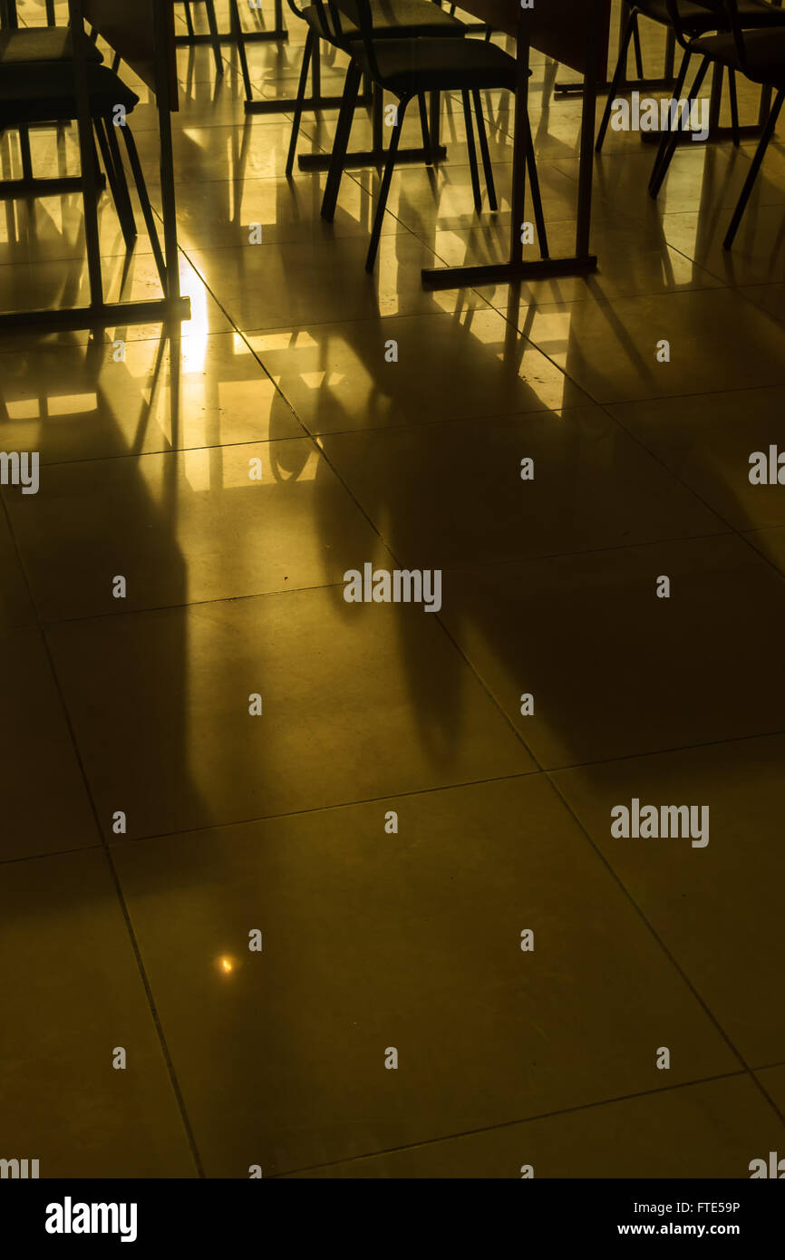 Righe e righe di conferenza vuota sedie catturati nella luce naturale del sole in una classe in ambiente scolastico. Nei toni del giallo con immagine Foto Stock