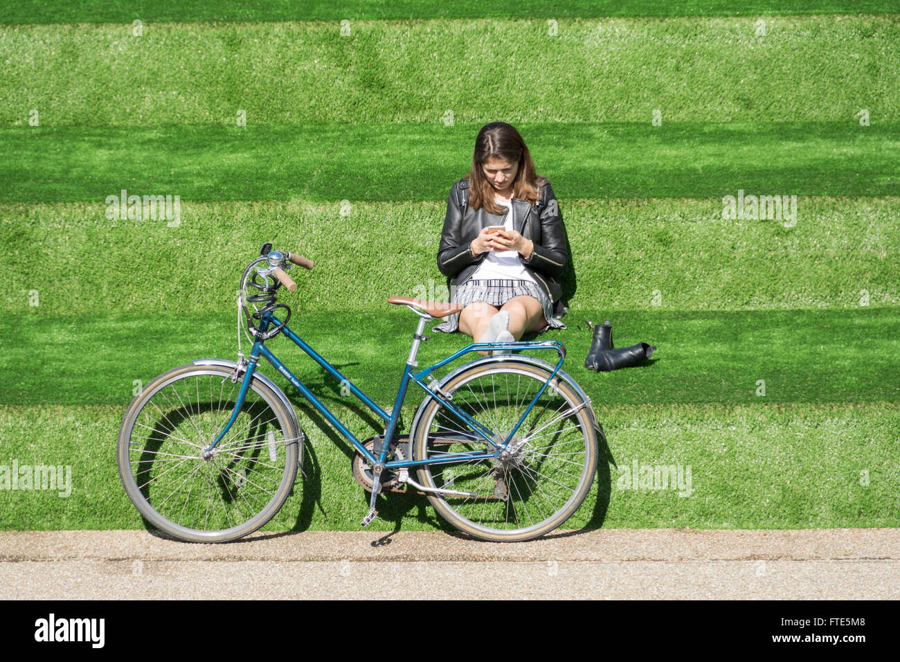 Giovane donna rilassante in Piazza Granaio, King's Cross, vicino a Regent's Canal, London, England, Regno Unito Foto Stock
