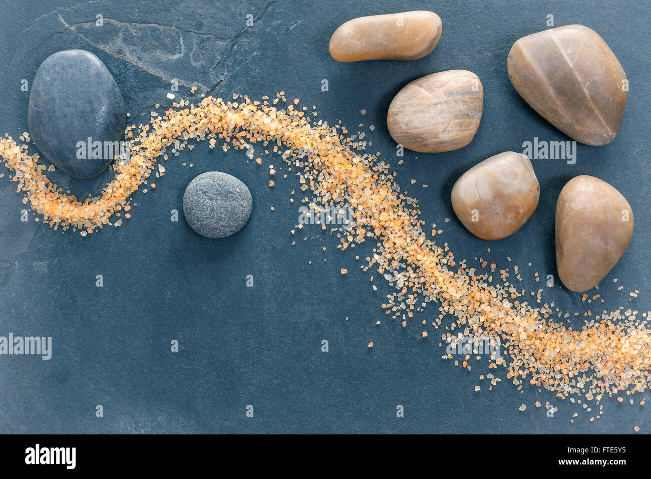 Vintage pietre filtrato su ardesia scuro dello sfondo con i sali da bagno, centro termale e di benessere o ancora la vita dello sfondo. Foto Stock