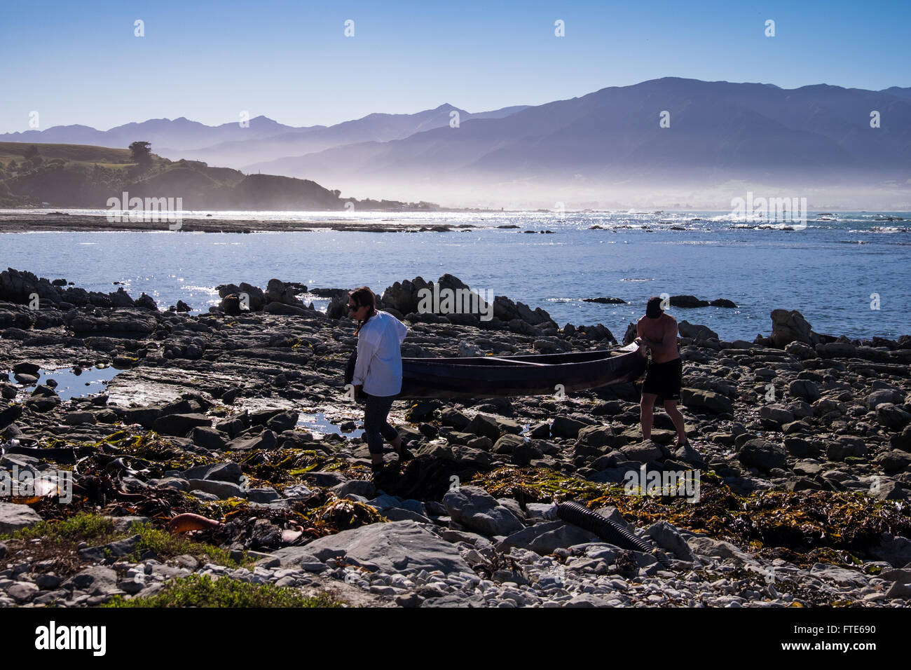 Persone che trasportano i loro canoe su roccia sulla penisola a Kaikoura Foto Stock