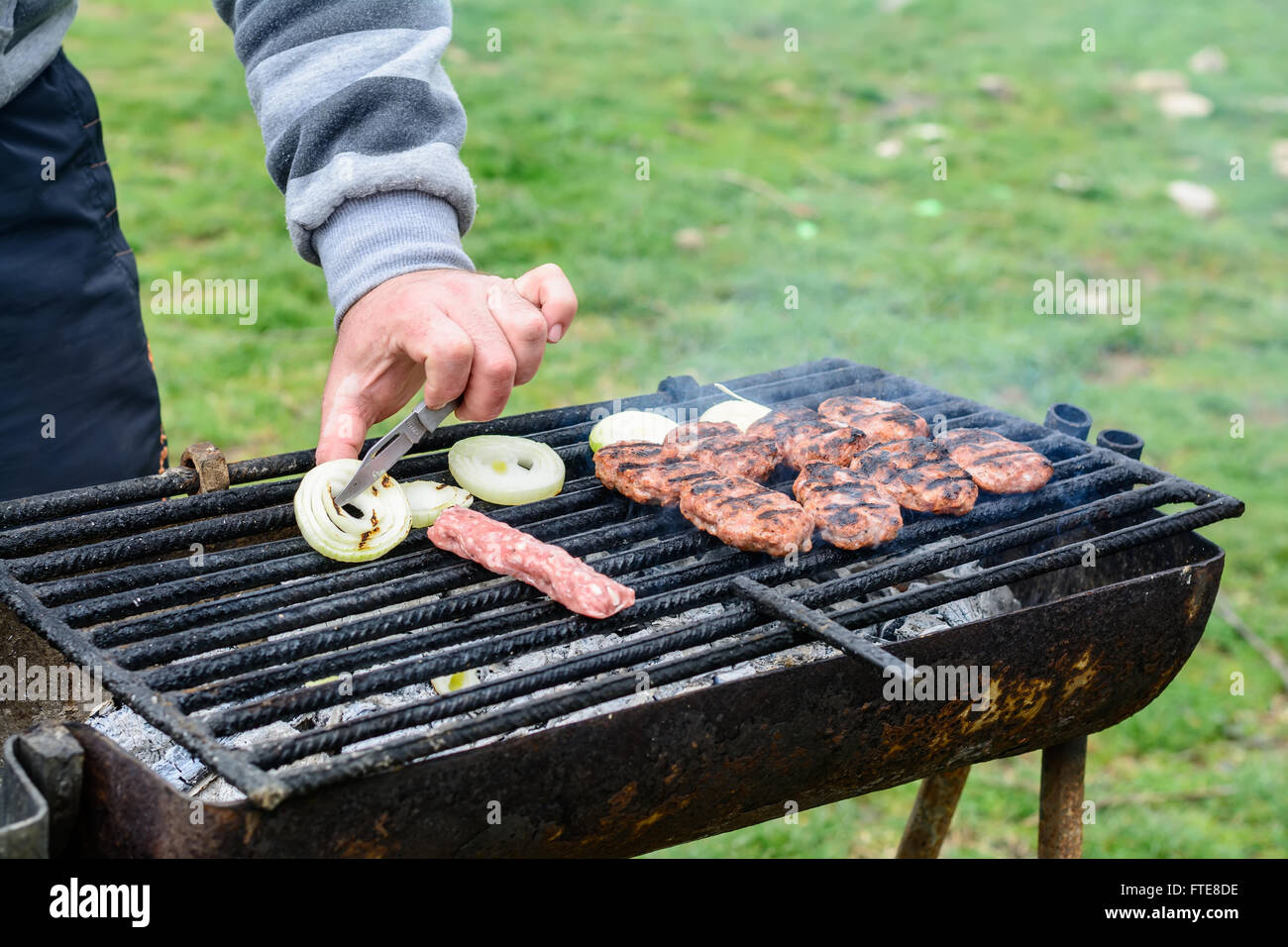 Barbecue esterno. Gli uomini della mano le polpette di carne cotta alla griglia. Foto Stock