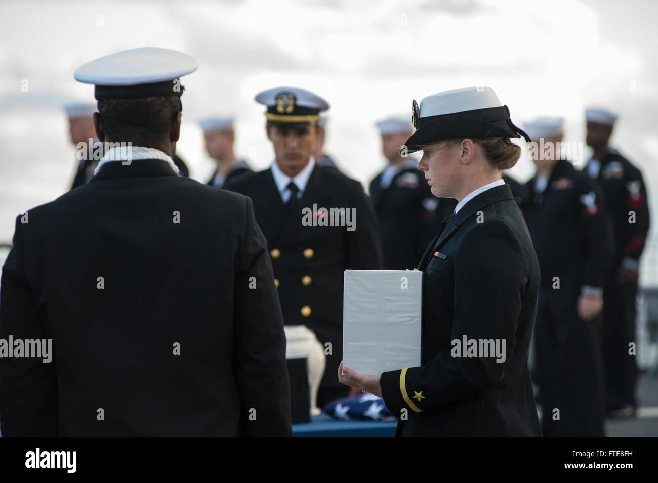Questa immagine raffigura la cerimonia di sepoltura in mare tenutasi sul ponte di volo della USS Ramage, con l'insegna Bryn Moriarty che tiene le ceneri da spalmare sul Mar Mediterraneo. La cerimonia evidenzia la solennità delle tradizioni marittime e delle operazioni militari. Foto Stock