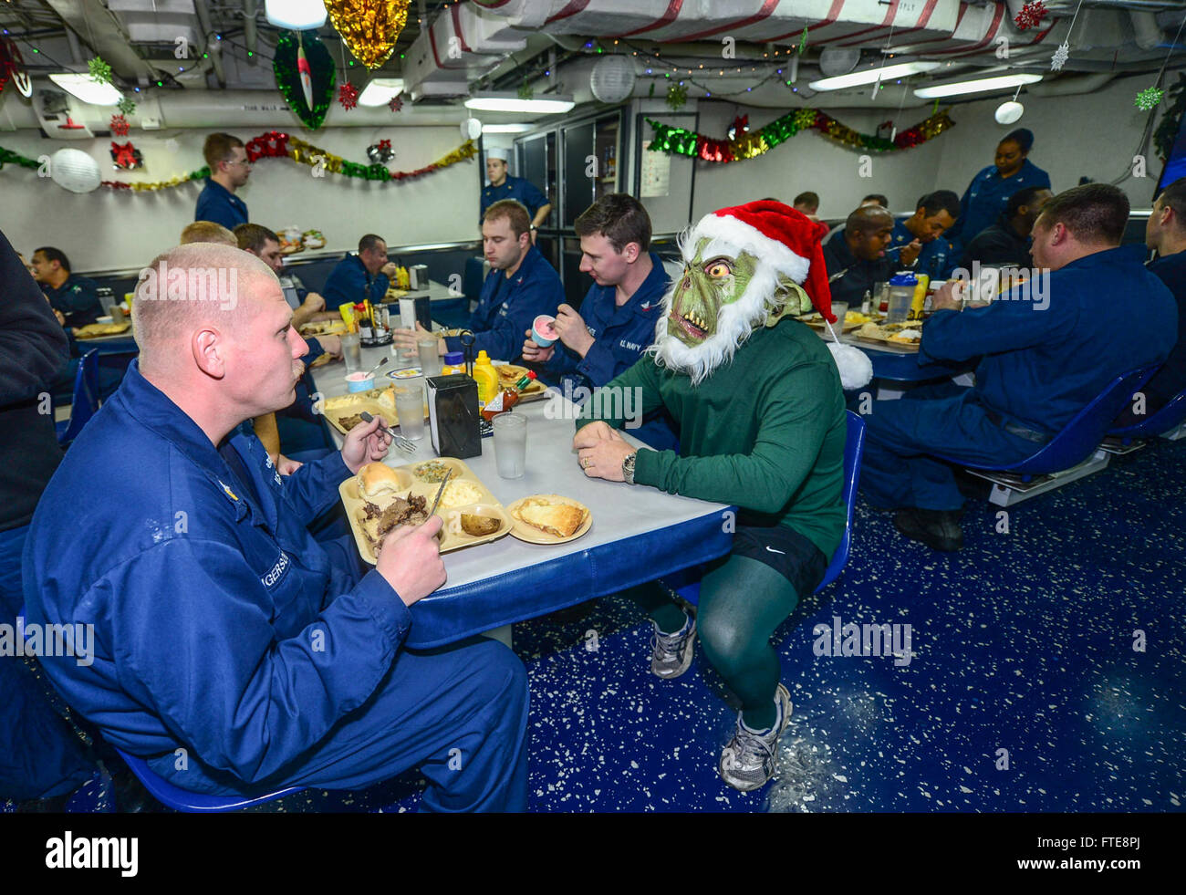 Il comandante Master Chief Lawrence Linton dell'USS Monterey (CG 61) si traveste da Grinch per la cena di Natale della nave, aggiungendo allegria festiva ai mess deck, durante il dispiegamento della nave a supporto delle operazioni di sicurezza marittima nell'area di operazioni della 6a Flotta degli Stati Uniti. Foto Stock