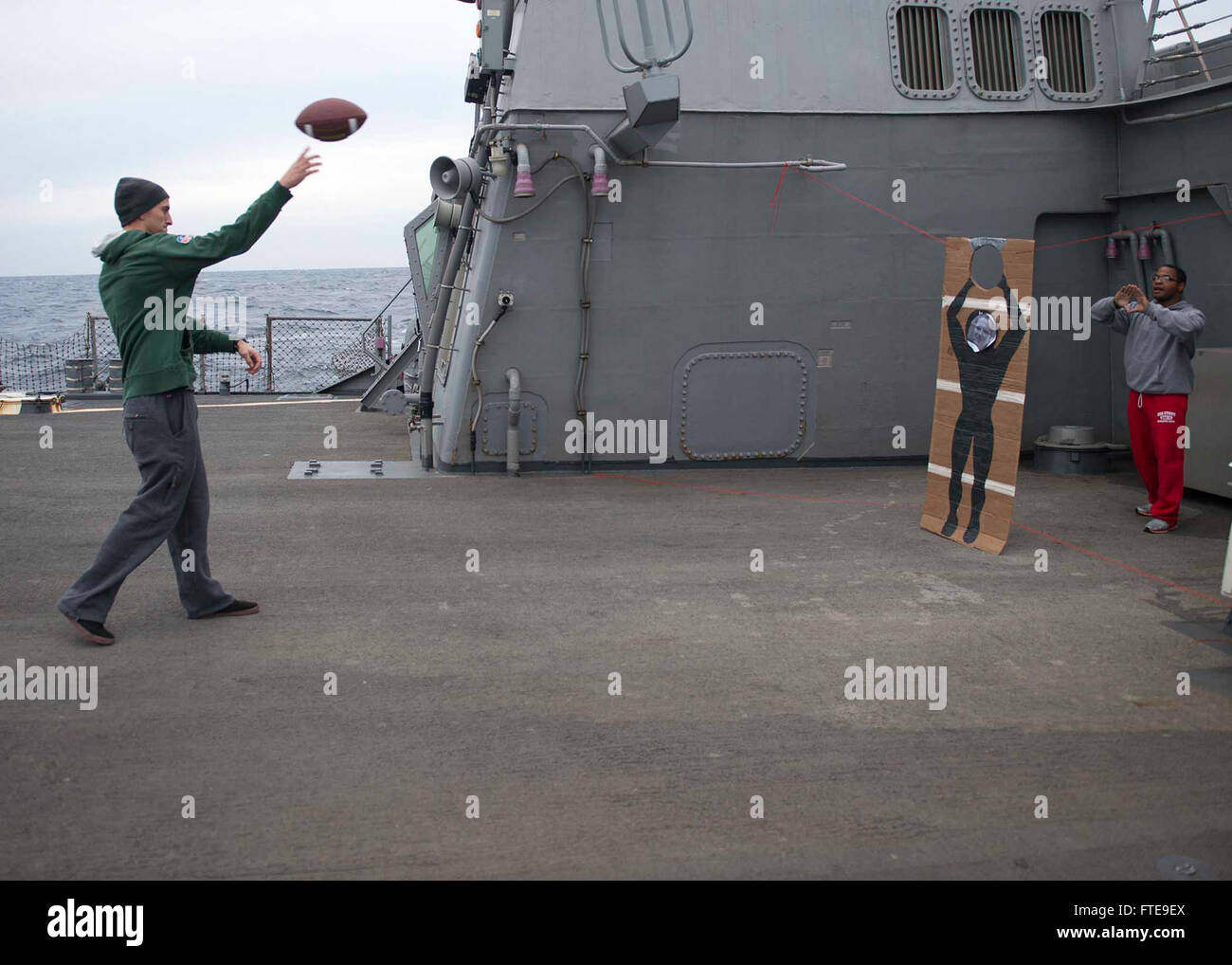Il 2 febbraio 2014, Marc Hibner e lo specialista logistico di terza classe Eugene Hogan hanno preso parte ad una competizione di lancio di calcio sul ponte di volo della USS Stout (DDG 55). La USS Stout fu schierata nel Mar Mediterraneo, sostenendo la sicurezza marittima e le operazioni navali degli Stati Uniti. Foto Stock
