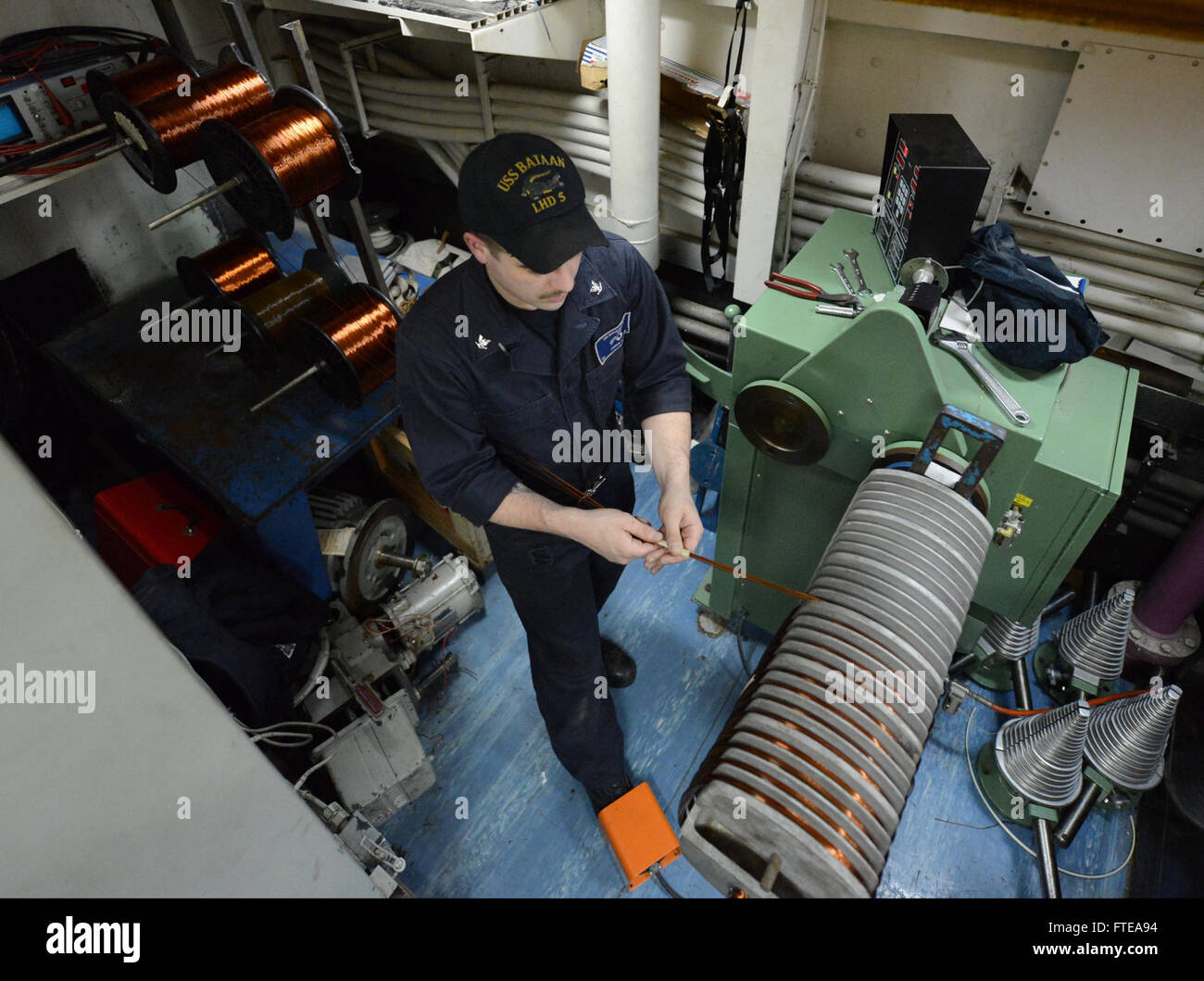 Il cannone Kaleb di 3a classe, elettricista, avvolge il filo di rame su una bobinatrice a bordo della USS Bataan (LHD 5) mentre è schierato nell'Oceano Atlantico. La USS Bataan fa parte di uno schieramento di supporto alle operazioni di sicurezza marittima nelle aree di responsabilità della 5a e 6a flotta degli Stati Uniti. Foto Stock