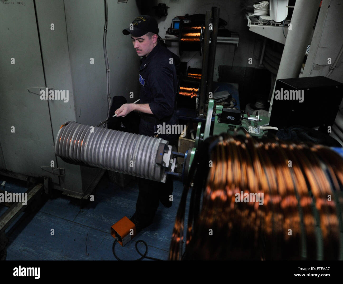 Il cannone Kaleb di 3a classe dell'elettricista avvolge il filo di rame su una macchina di avvolgimento a bordo della USS Bataan (LHD 5). Il Bataan è schierato a sostegno delle operazioni di sicurezza marittima e degli sforzi di cooperazione per la sicurezza del teatro all'interno delle aree di responsabilità della 5a e 6a flotta della Marina degli Stati Uniti. Foto Stock