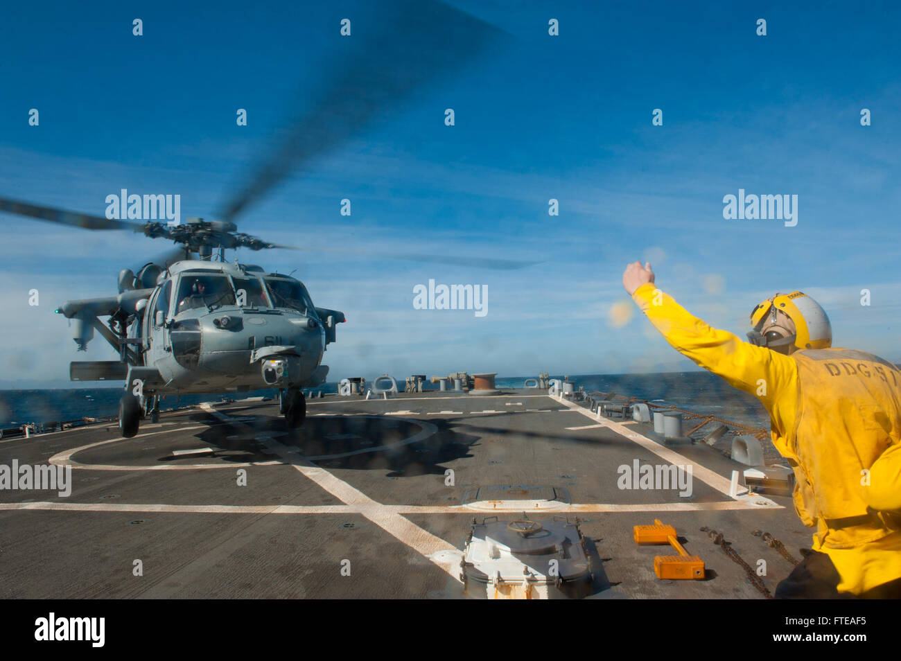 Il Mate Darin Kent di Boatswain segnala a un elicottero MH-60R Sea Hawk mentre si prepara ad atterrare a bordo della USS Arleigh Burke (DDG 51) durante un transito attraverso lo stretto di Gibilterra. L'Arleigh Burke è schierato a sostegno degli sforzi di cooperazione in materia di sicurezza marittima nelle aree della 5a e 6a flotta statunitense. Foto Stock