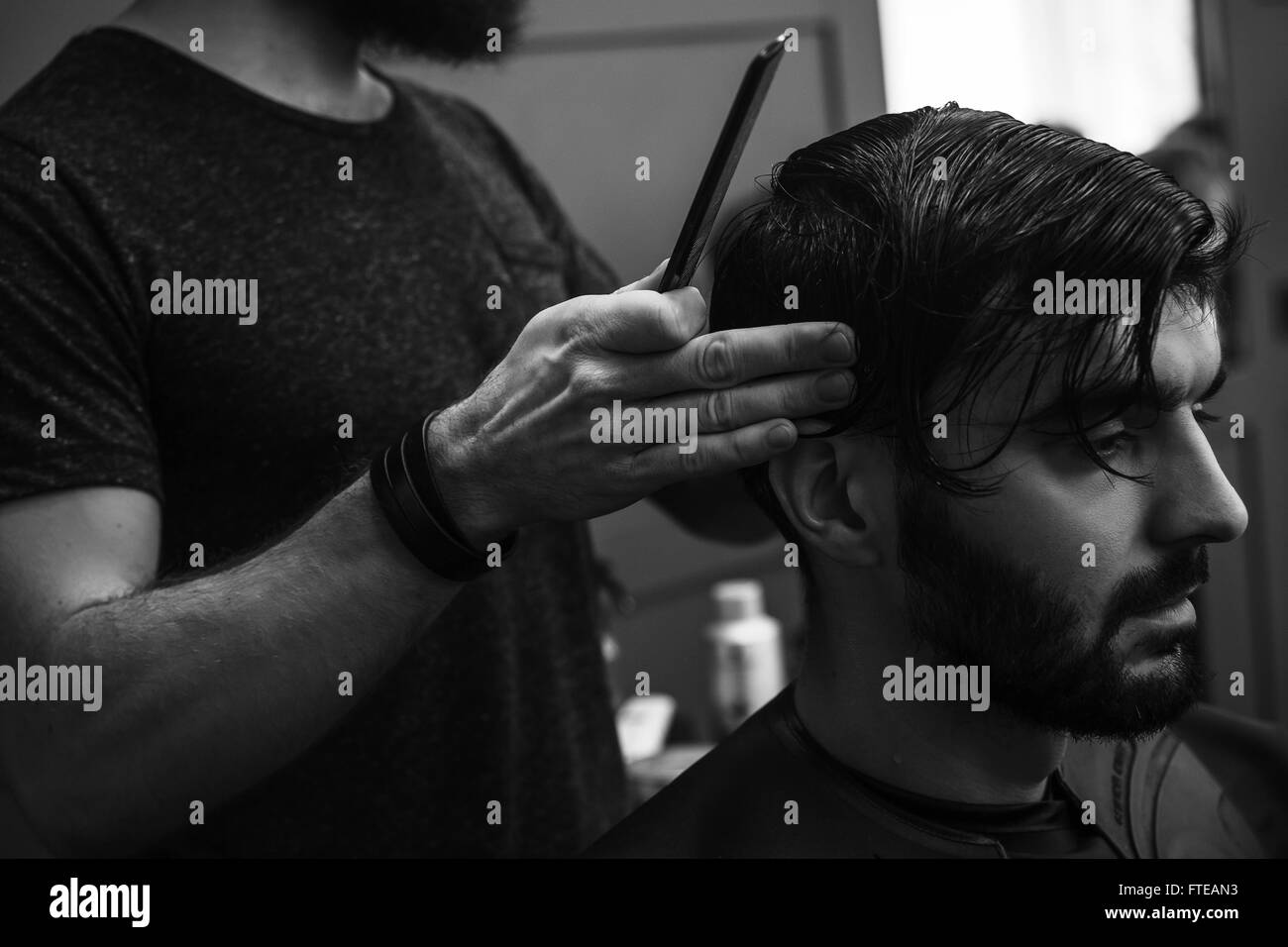 Barbiere maschio pettinatura e la rasatura dei capelli di un client maschio Foto Stock