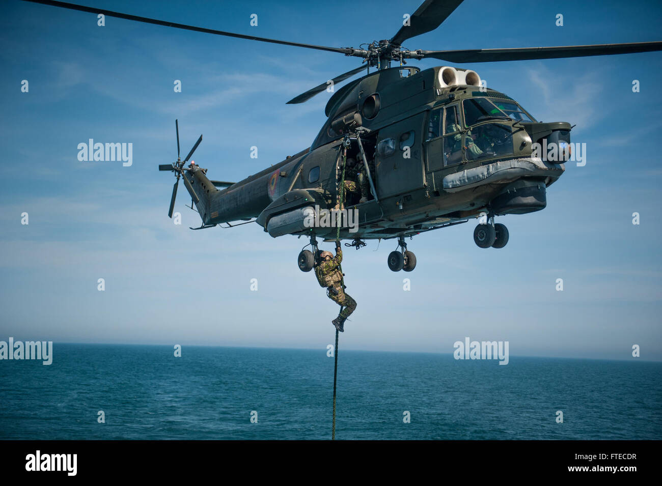 Le forze speciali rumene conducono una manovra a fune veloce da un elicottero IAR 330 Puma alla USS Truxtun, un cacciatorpediniere di missili guidati classe Arleigh Burke, durante un esercizio di addestramento. Questo esercizio fa parte della cooperazione in materia di sicurezza marittima e di sicurezza del teatro nell'area operativa della 6th Fleet degli Stati Uniti. Foto Stock